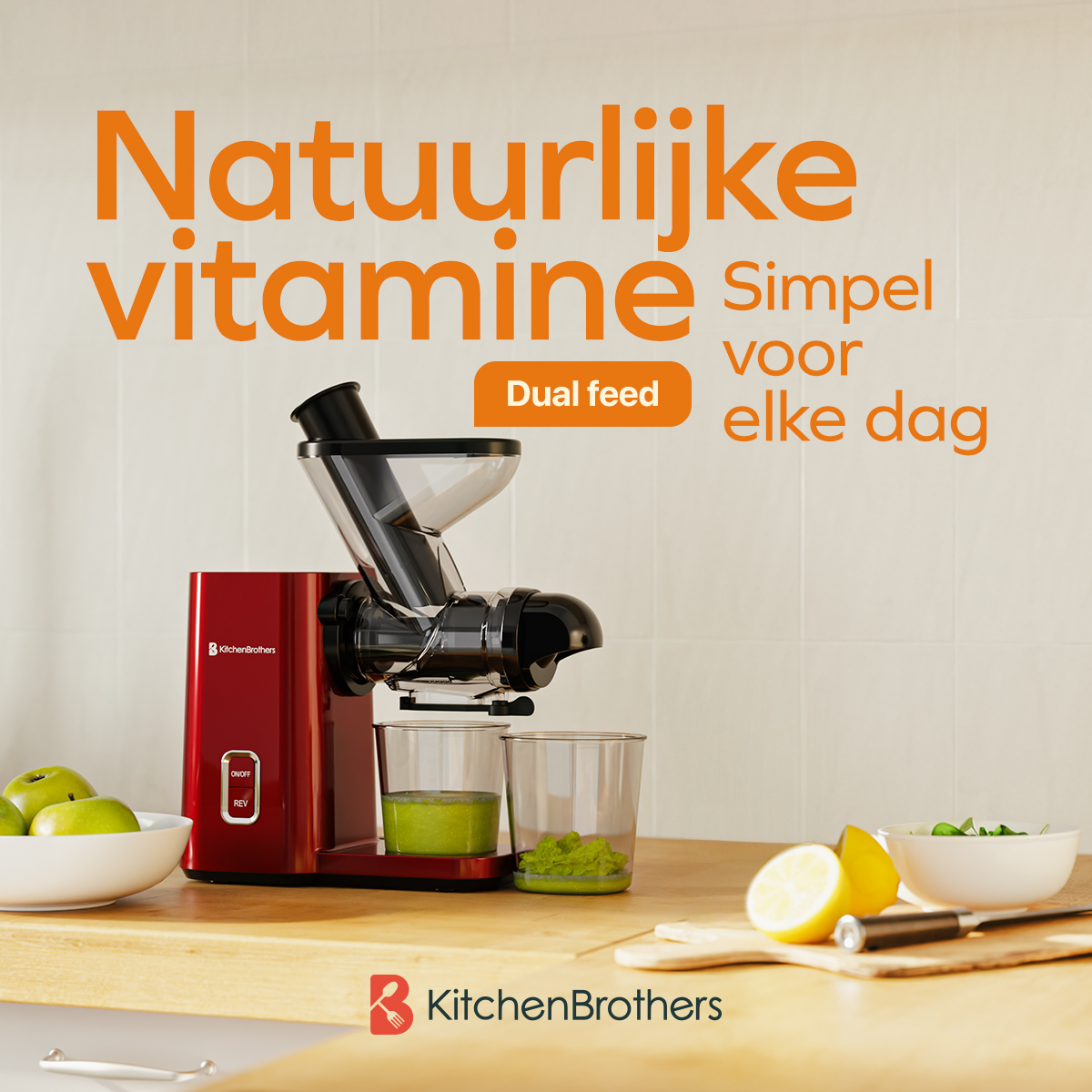 A red KitchenBrothers juicer on a wooden table with fruit and vegetables, set against a white tiled wall.