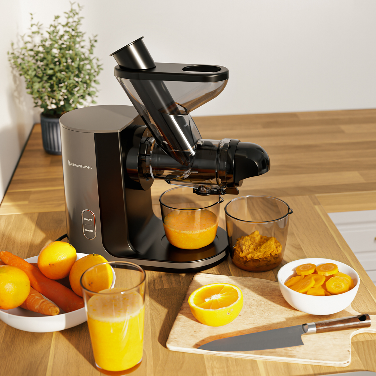 A black KitchenBrothers juicer on a wooden table, surrounded by oranges, carrots, and juice.