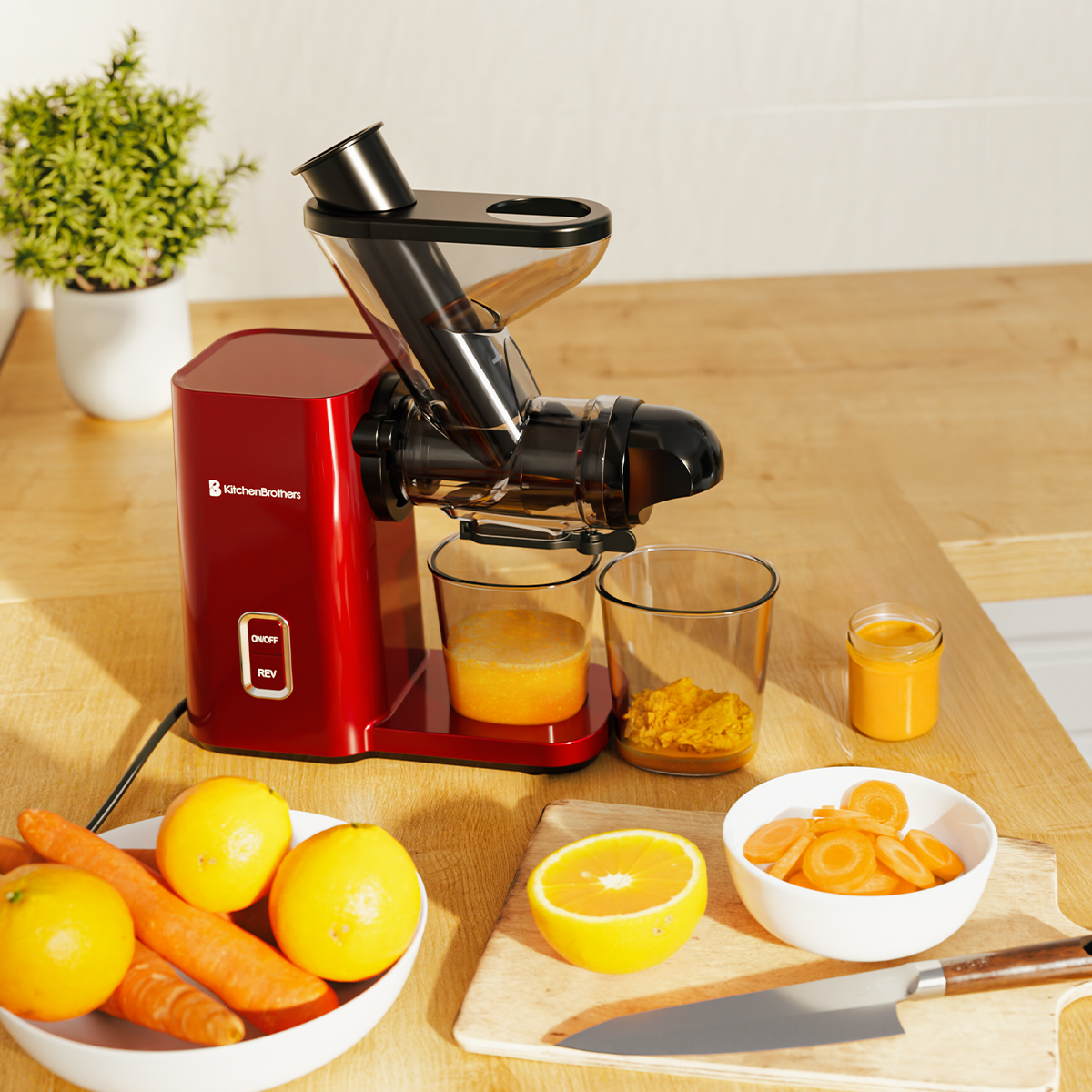 A red juicer is on a wood counter with oranges, carrots, and juice.