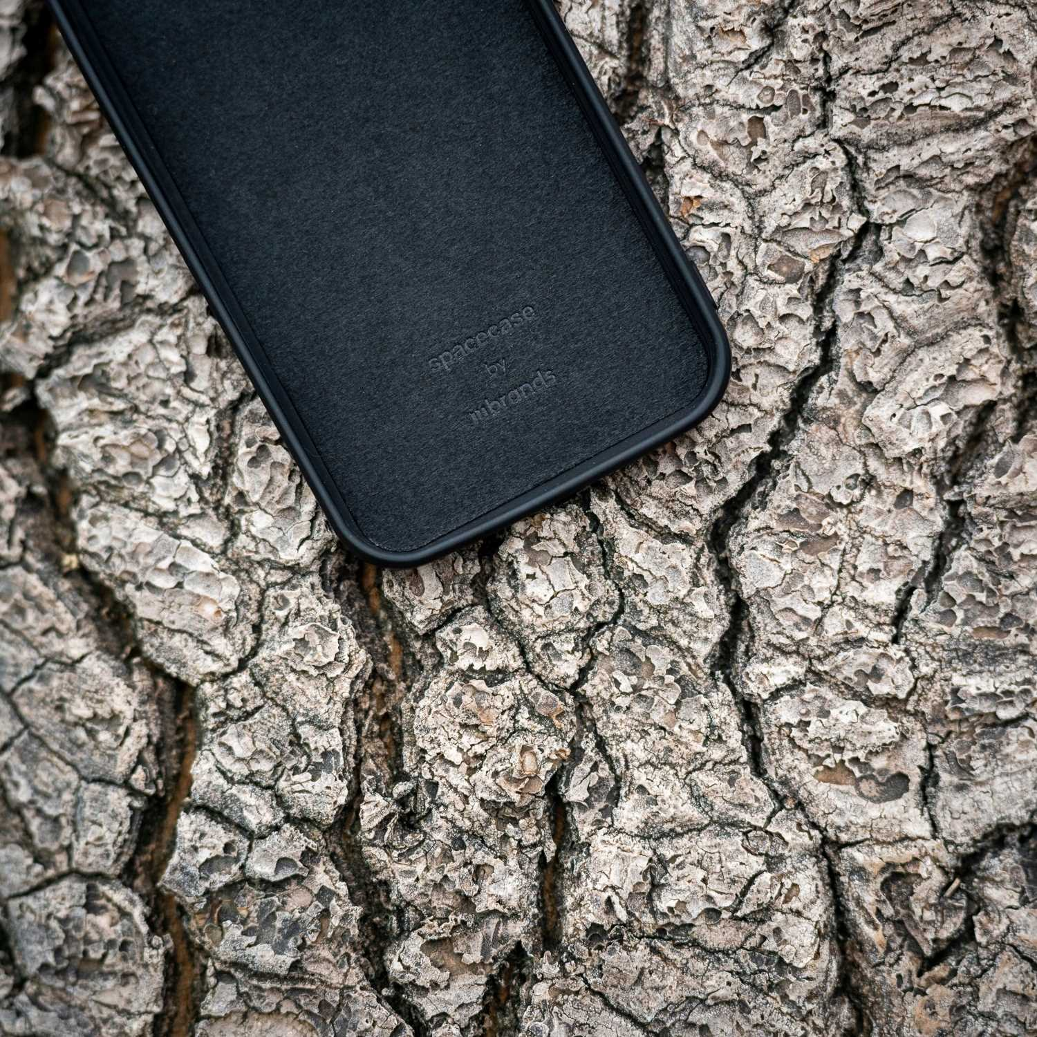 Czarne etui na telefon na teksturowanej korze drzewa.