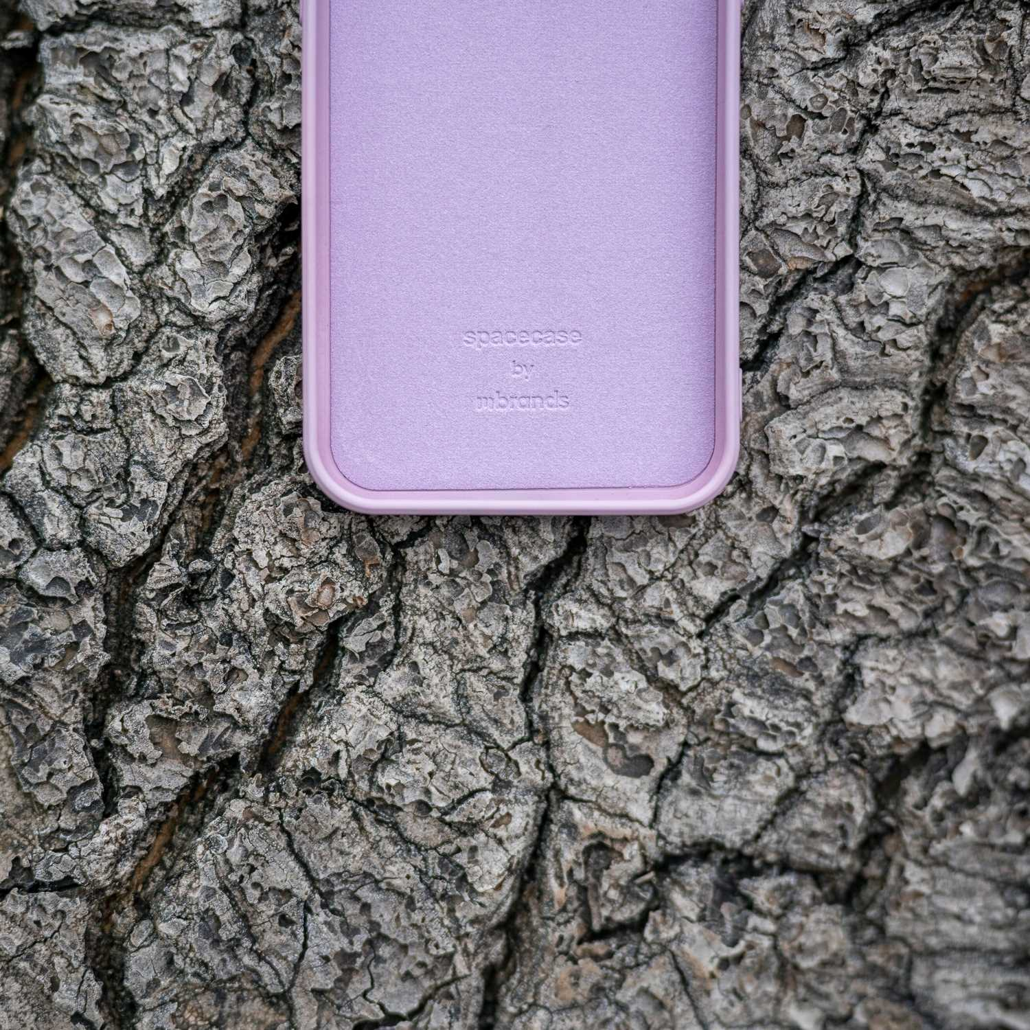 Zbliżenie liliowego etui na telefon na teksturowanej korze, z nadrukiem „spacecase by mbrands”.