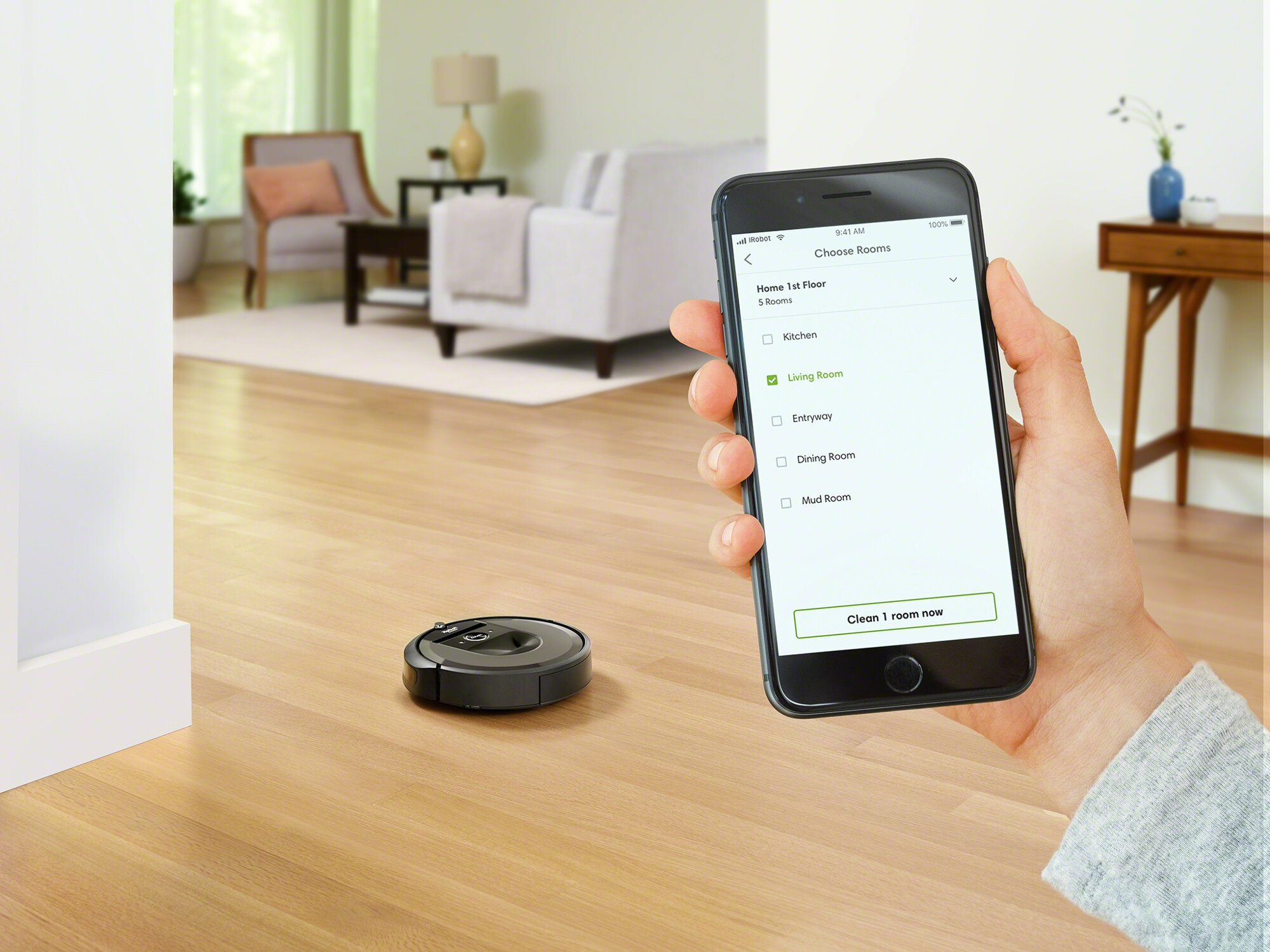 Un robot aspirateur noir et un smartphone dans un salon.