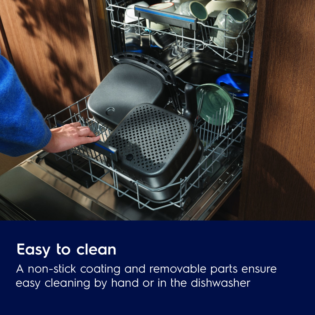 Zmywarka z ręką umieszczającą przedmioty. Przedmioty to czarne i szare pojemniki.