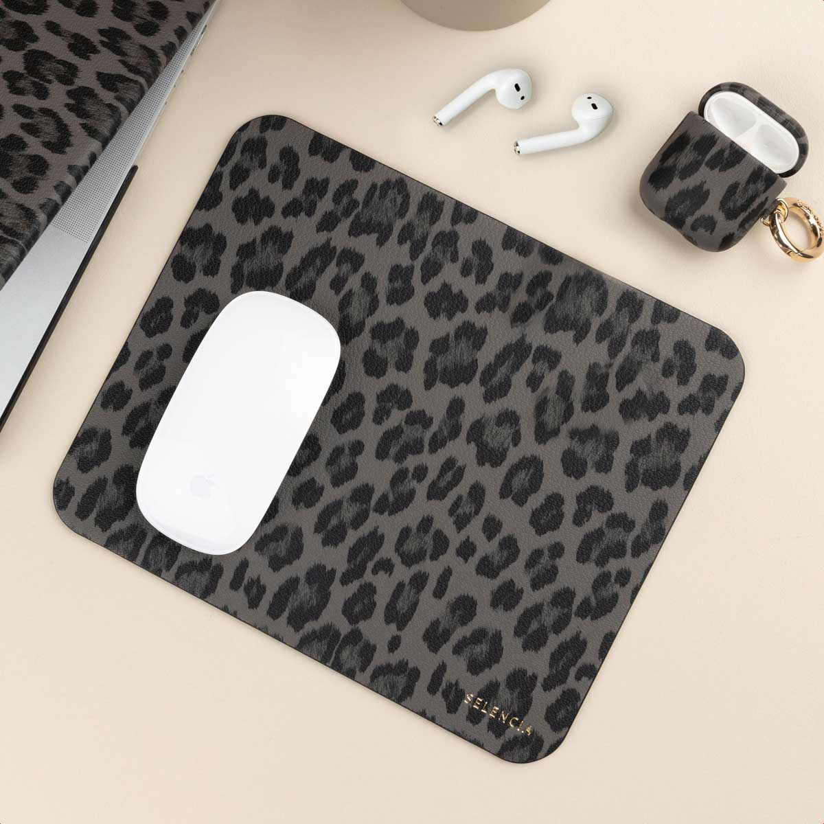Mousepad with gray leopard print, white mouse, and gray leopard print earbud case on a desk.