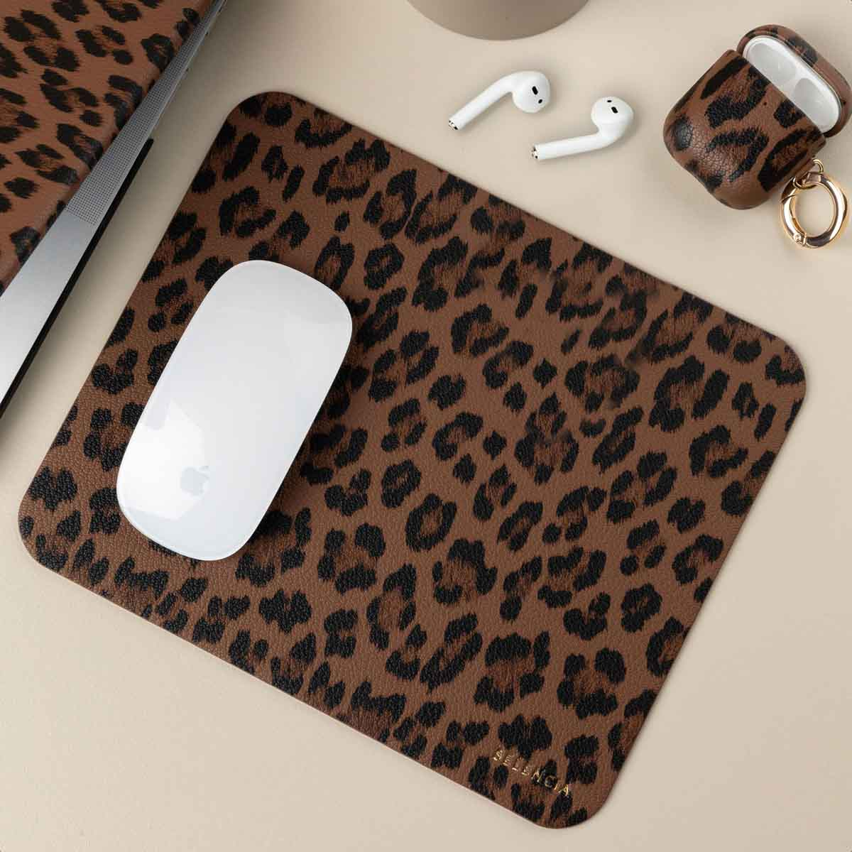 A leopard print desk mat with a white mouse, AirPods, and AirPod case on a light beige background.