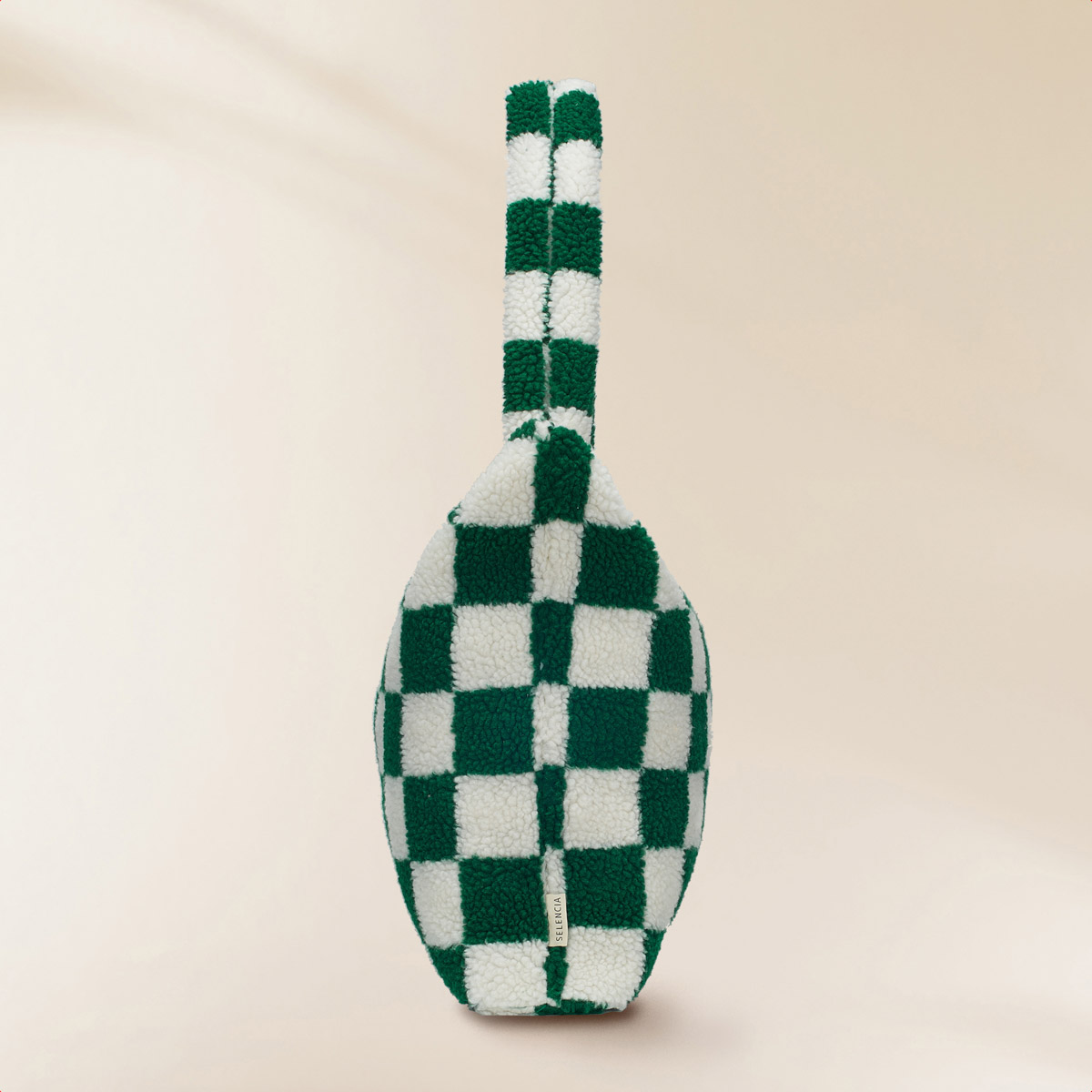 A green and white checkered faux fur bag with a handle is against a neutral background.