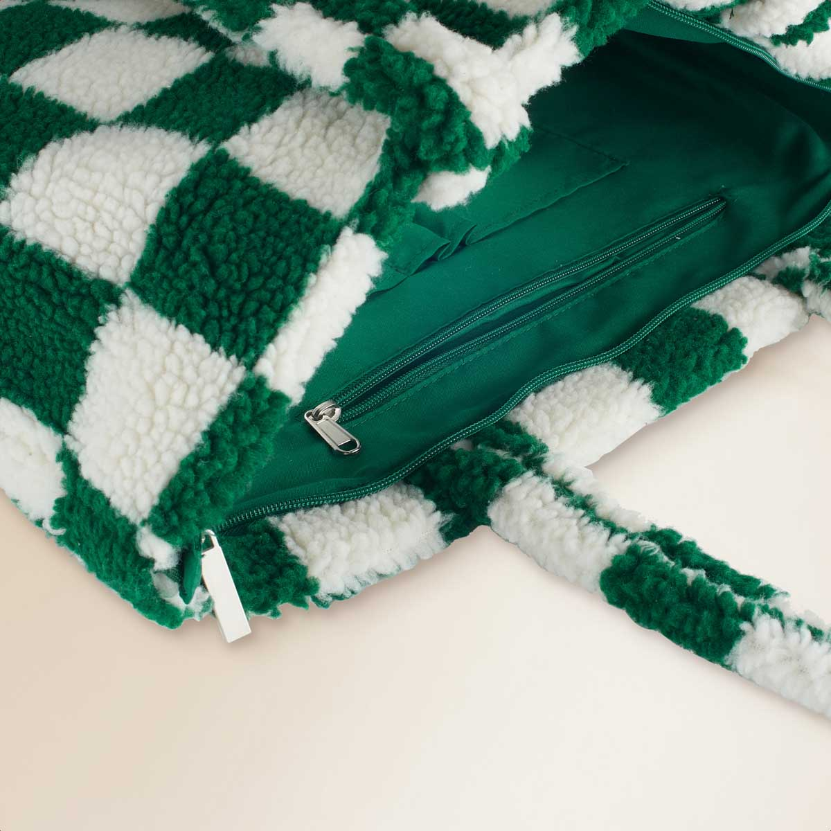 A green and white checkered bag with a zipper, revealing its green interior lining.