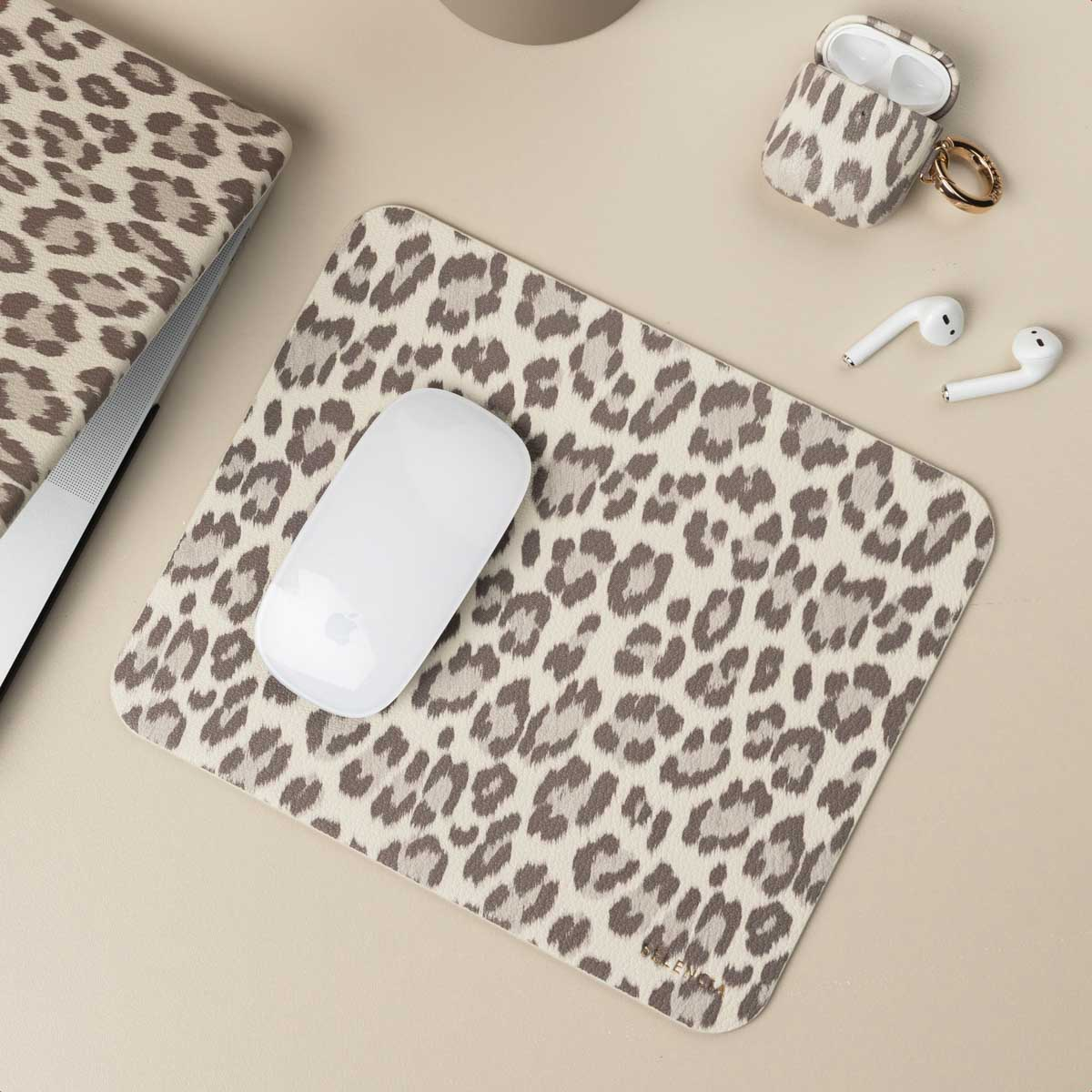 Leopard print desk setup with mousepad, laptop, AirPods, and mouse, showcasing a coordinated theme.