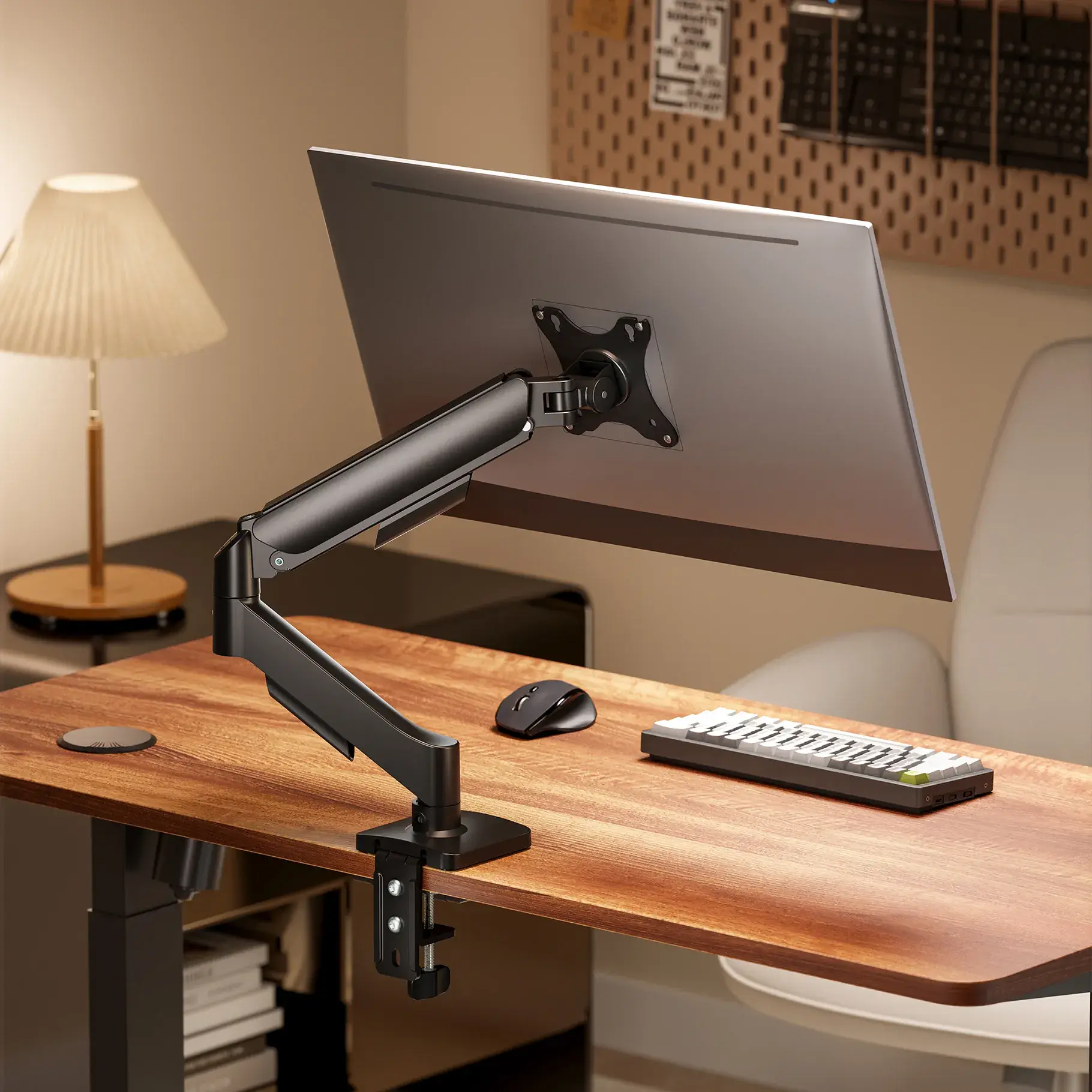 Un moniteur est monté sur un bureau avec un bras de moniteur noir, un clavier et une souris.