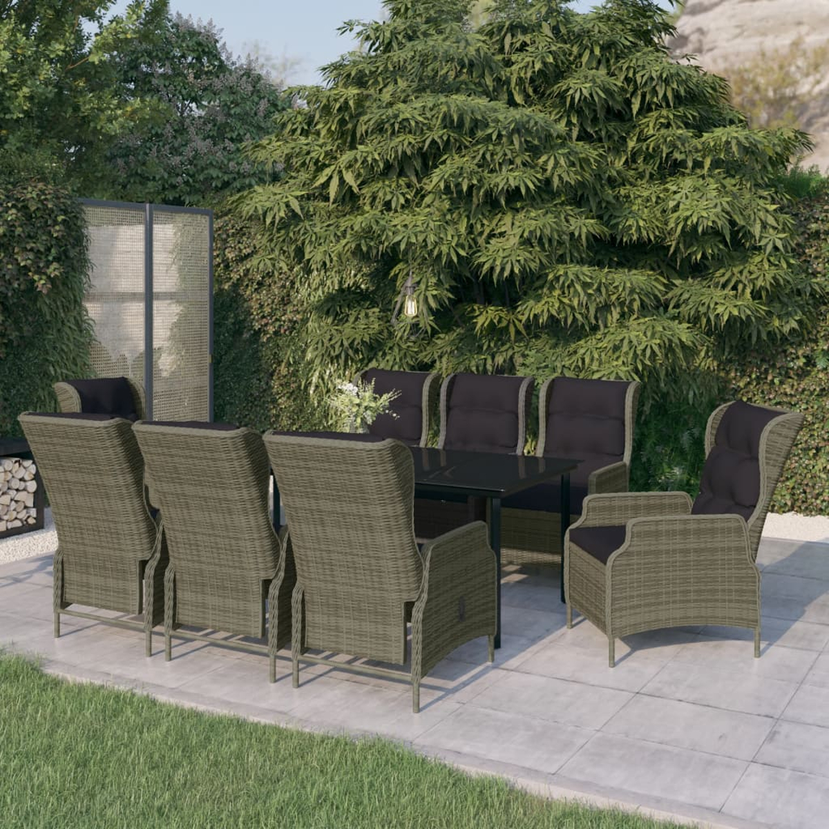 Outdoor-Essgruppe mit sechs Korbstühlen und einem schwarzen Tisch auf einer Terrasse, umgeben von üppigen grünen Bäumen und Blättern.