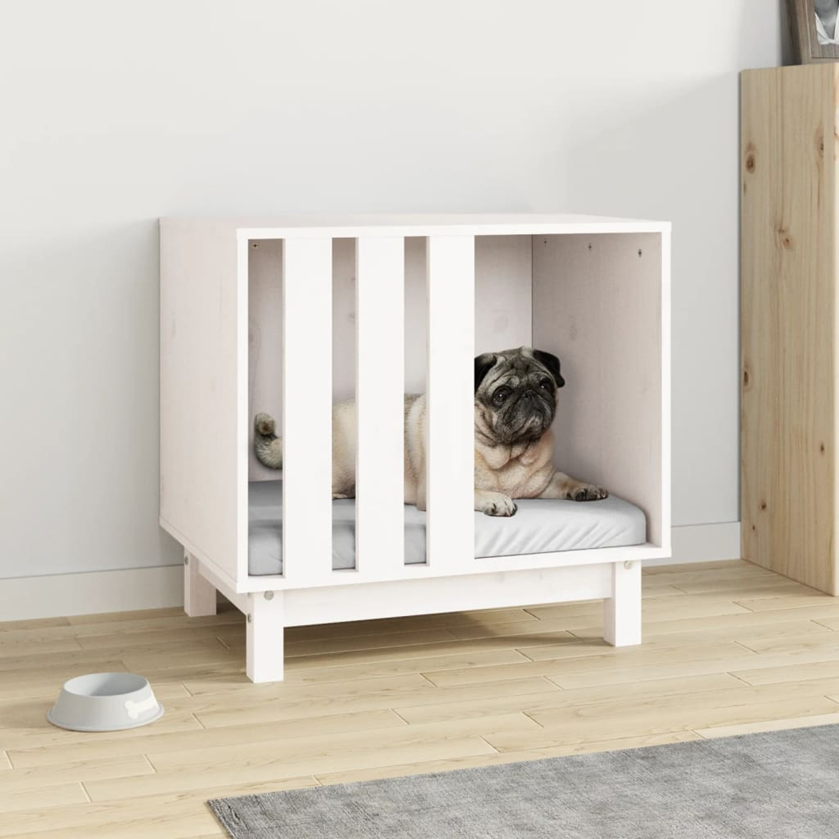 Ein Mops ruht in einem weißen Holz-Haustierhaus mit einem grauen Kissen neben einem grauen Futternapf.