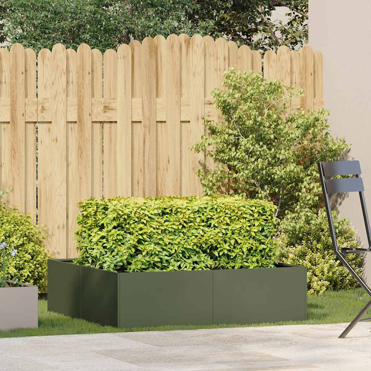 Fioriera quadrata verde oliva riempita con un arbusto verde in un ambiente esterno con recinzione e sedia.