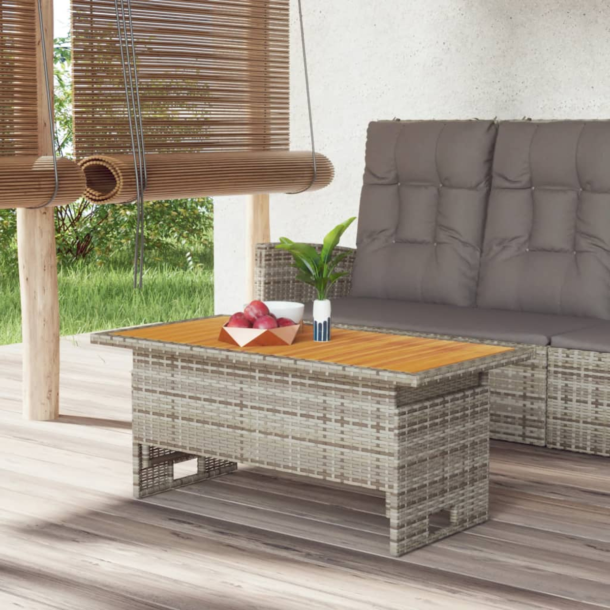 Eine Terrassenszene zeigt einen Korbtisch mit Obst, ein Sofa mit Kissen und Bambusrollos.