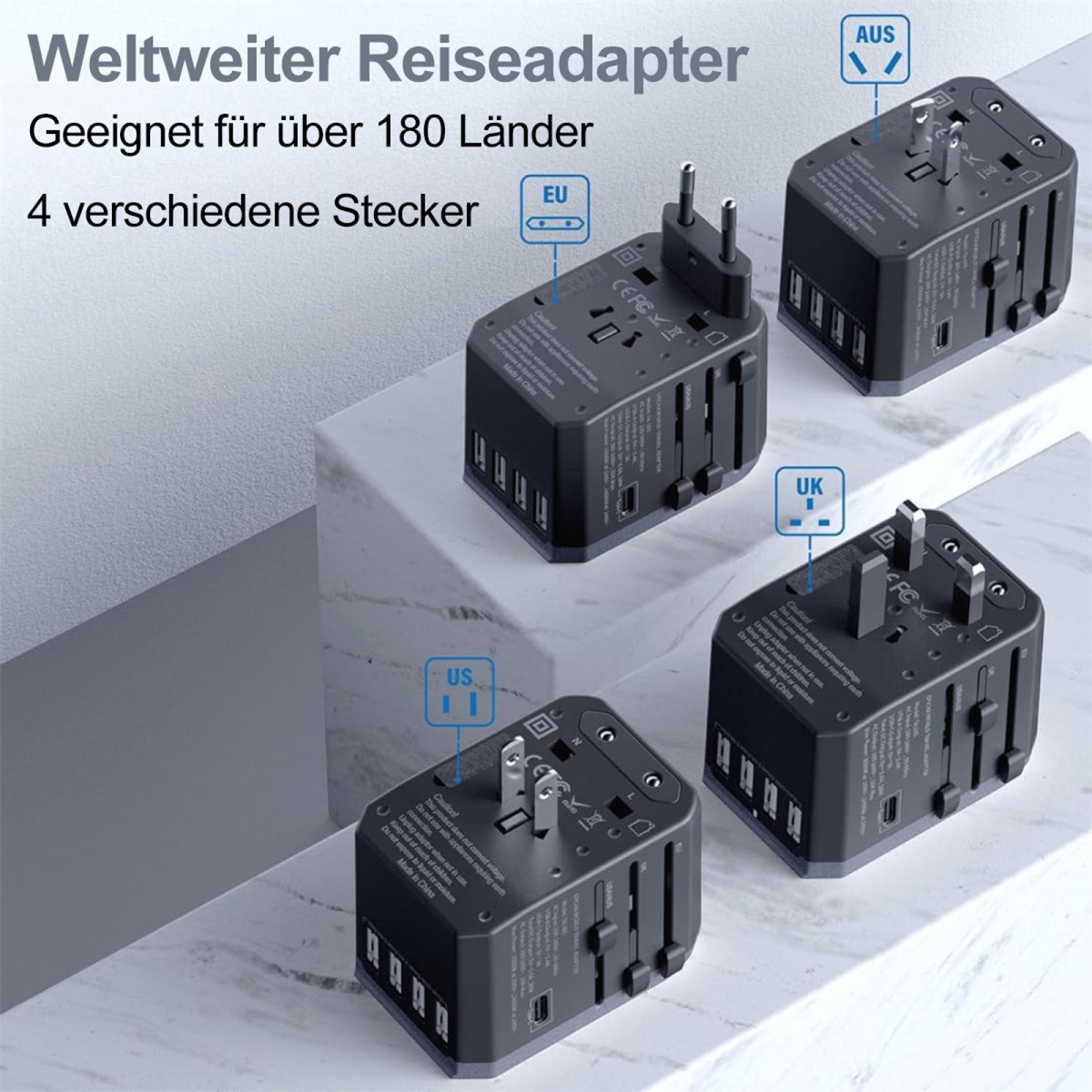Vier schwarze Universal-Reiseadapter sind auf einer Marmoroberfläche abgewinkelt, wobei jeder verschiedene Steckeranordnungen zeigt.