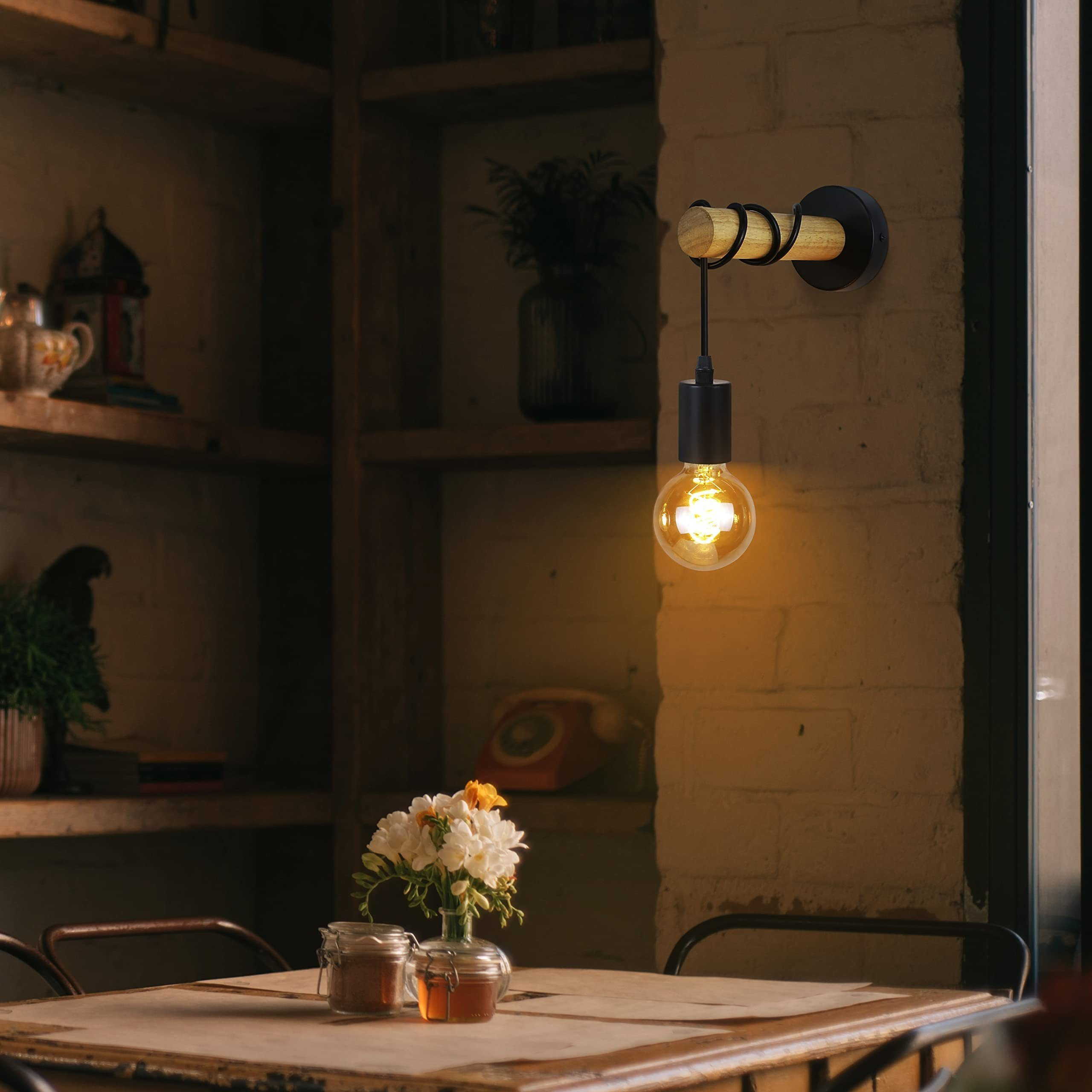 Una lampada da parete con un design in legno e metallo illumina una lampadina in un ambiente accogliente.