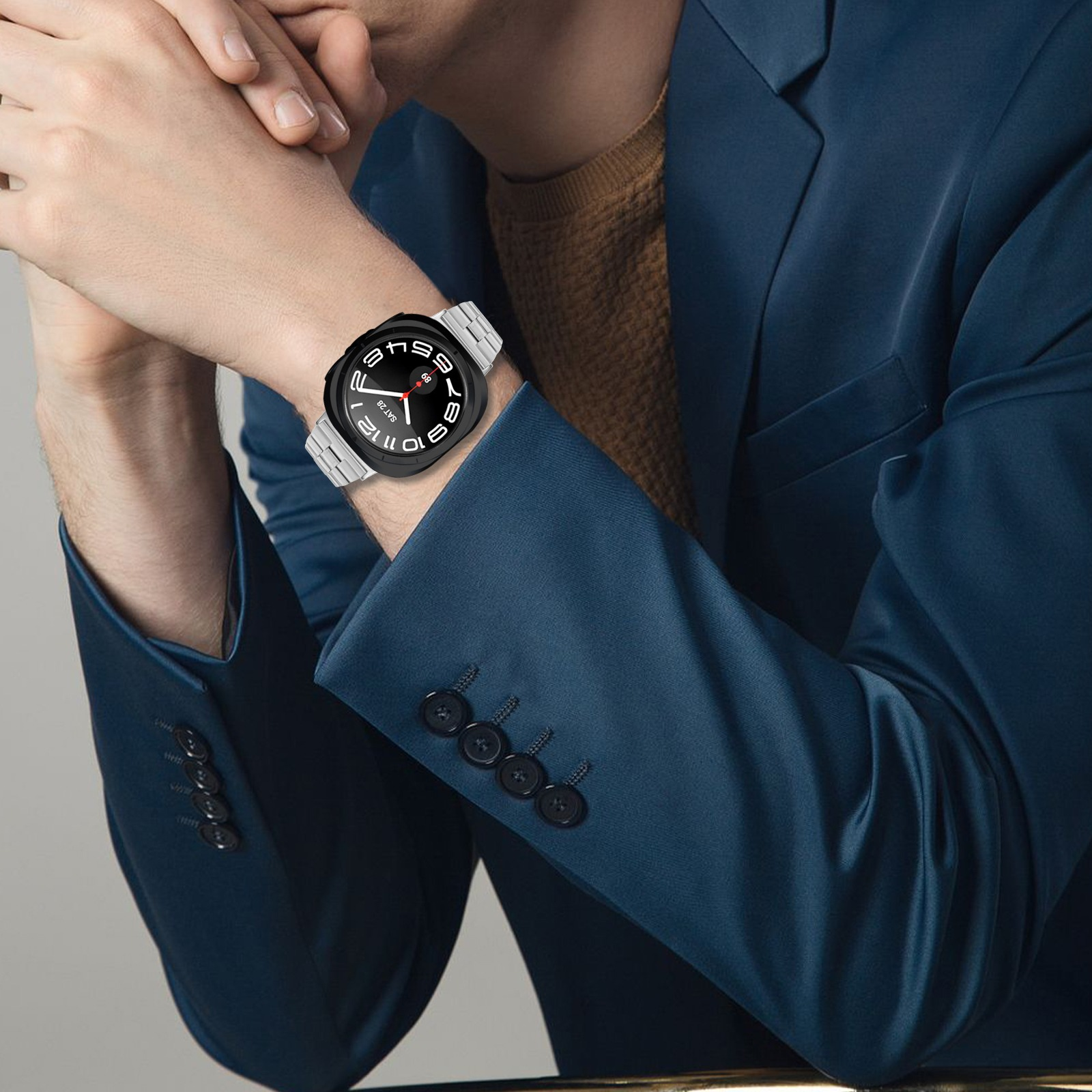 Ein Mann in einem blauen Anzug trägt eine Smartwatch mit einem silbernen Metallarmband und präsentiert die Uhr vor seiner Kleidung.