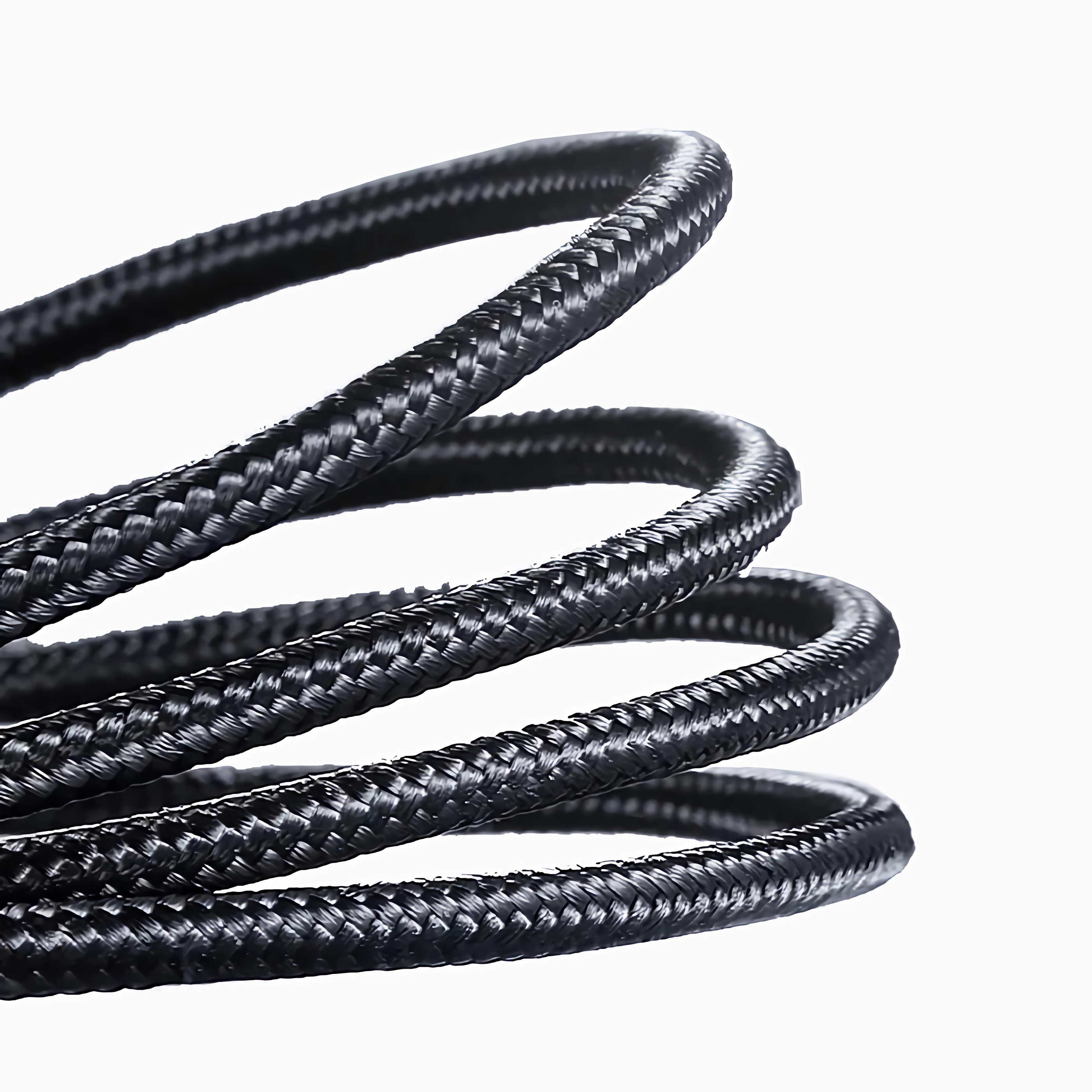Eine Nahaufnahme zeigt ein schwarzes geflochtenes Kabel, das aufgerollt ist und seine Textur vor einem weißen Hintergrund hervorhebt.