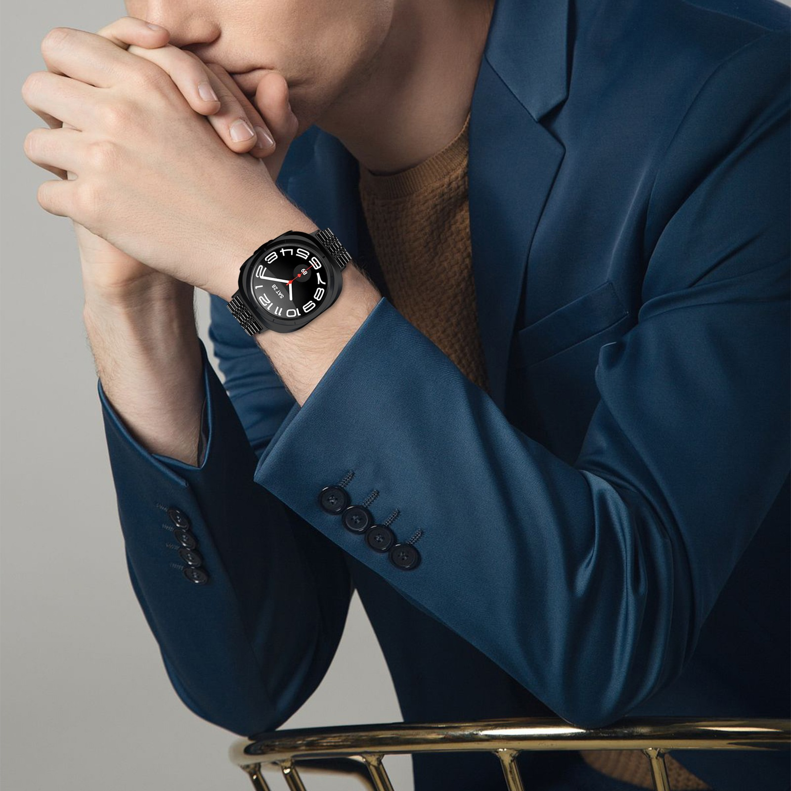 Un uomo indossa un orologio nero con quadrante bianco, completato da un abito blu.