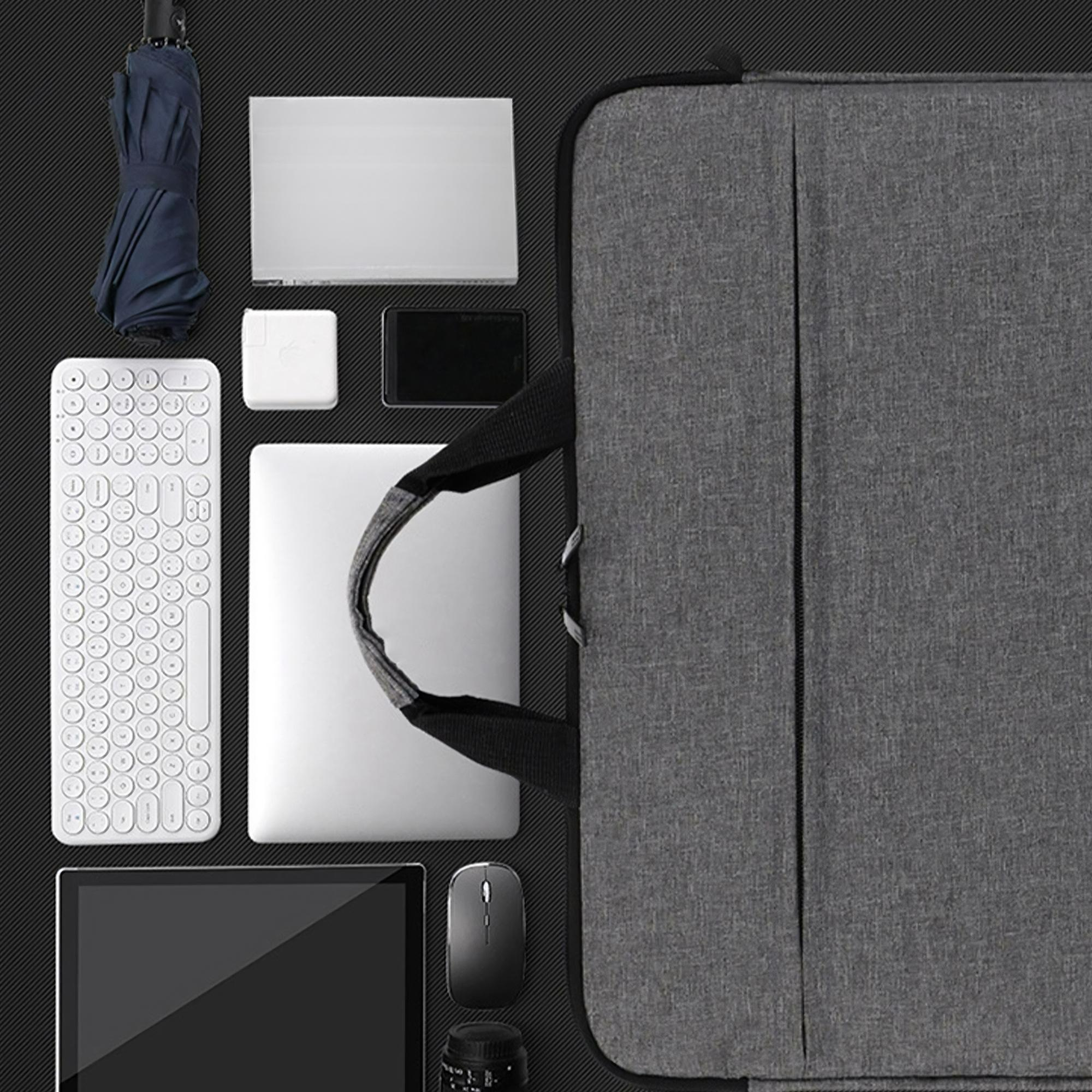 Draufsicht auf eine graue Laptoptasche mit Laptop, Tablet, Tastatur, Maus und Regenschirm auf schwarzem Hintergrund.