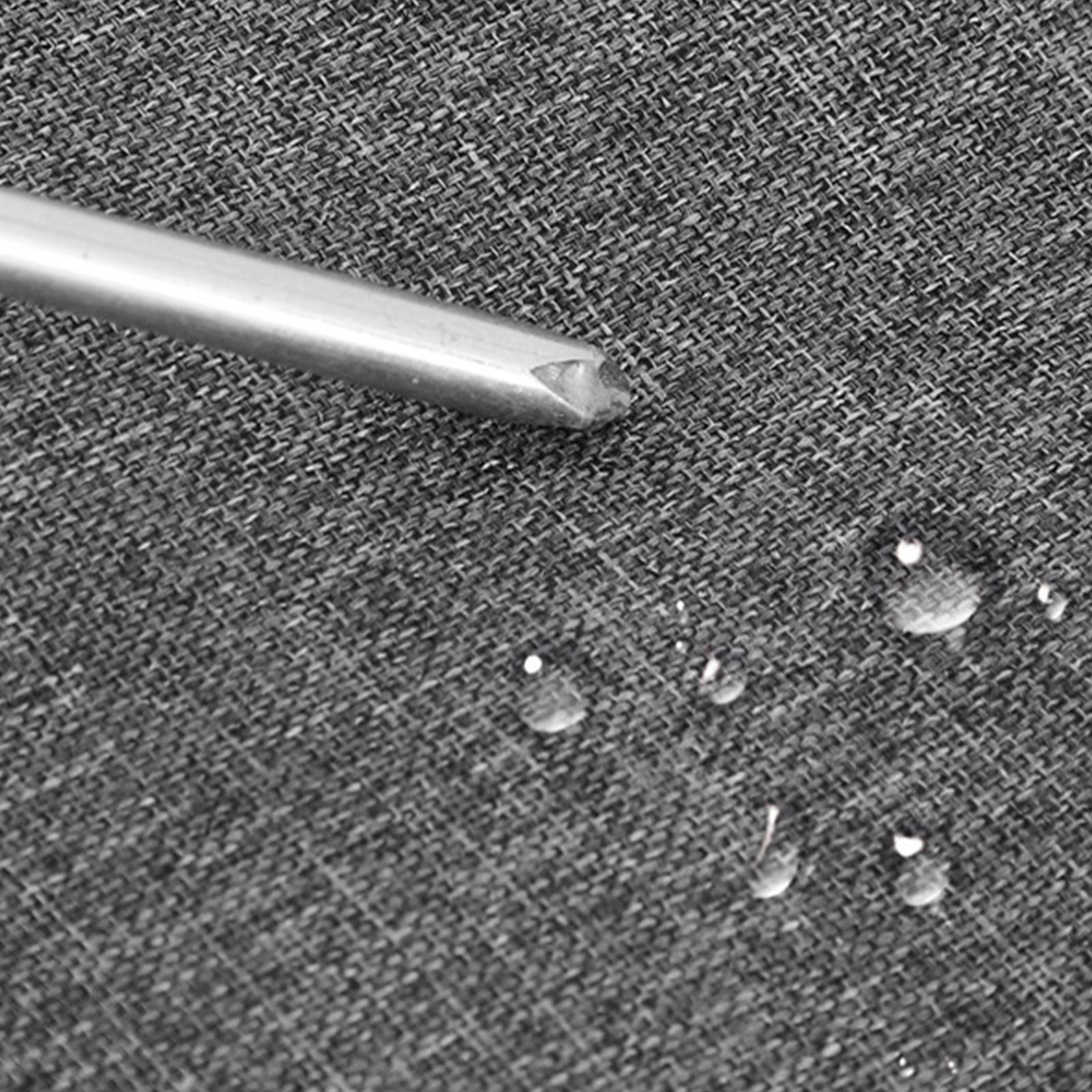Nahaufnahme von Wassertropfen auf grauem Stoff mit einer Metallspitze, die in das Material drückt.