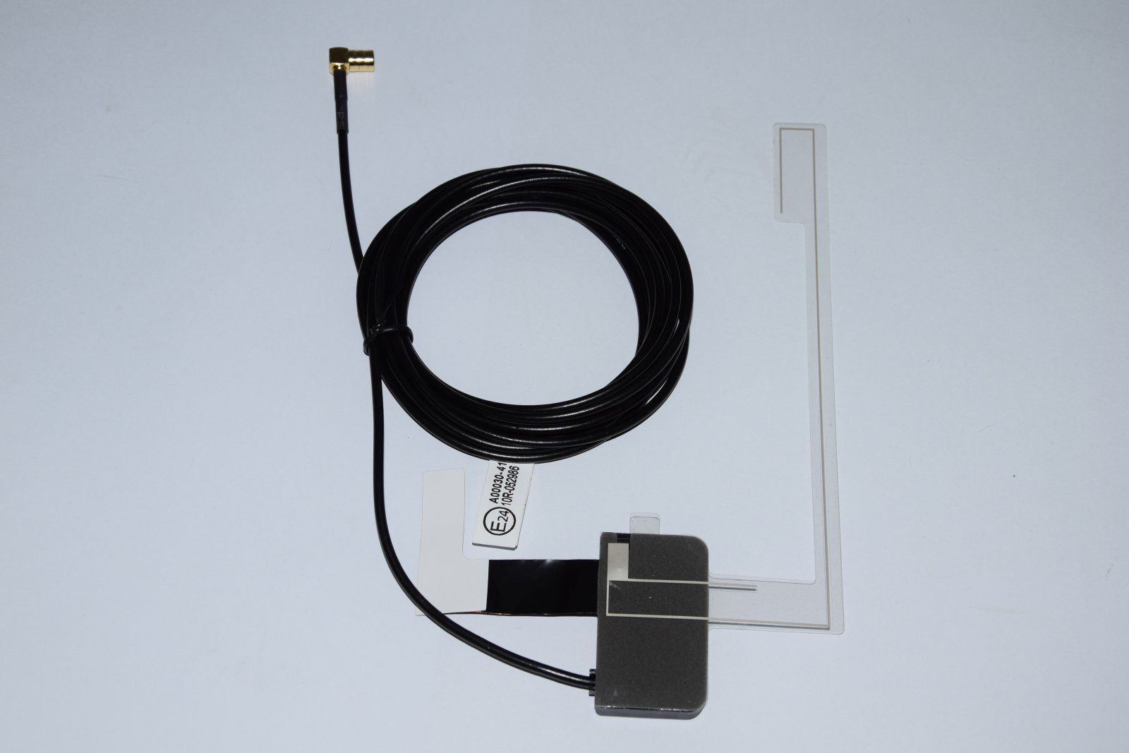 Cavo dell'antenna nero arrotolato e disposto su uno sfondo bianco con una staffa di plastica trasparente.