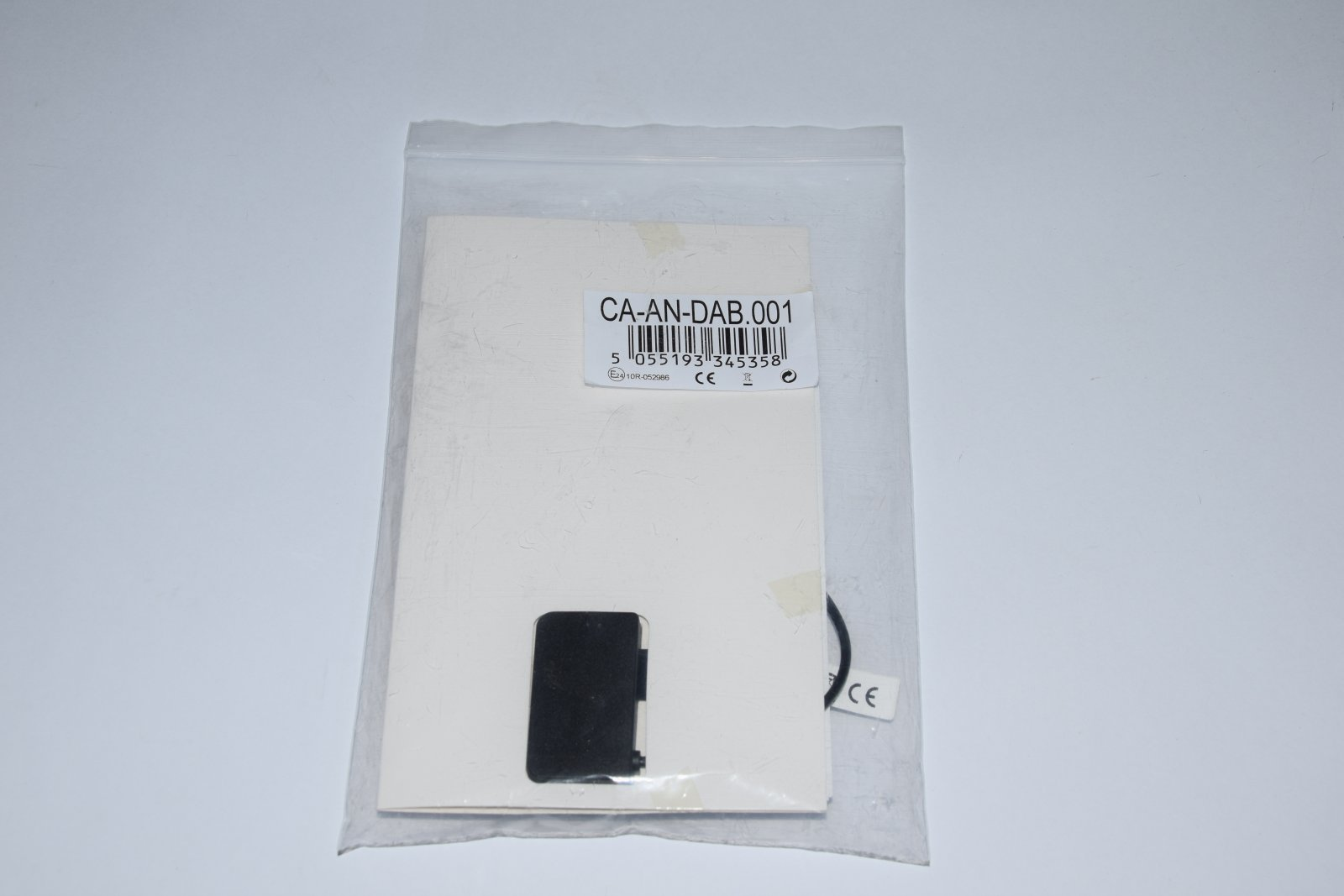 Sacchetto di plastica sigillato contenente una scheda bianca con testo e un componente nero.