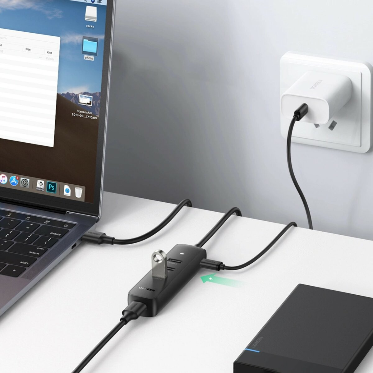 Koncentrator USB UGREEN podłączony do laptopa, dysku zewnętrznego i gniazdka elektrycznego.