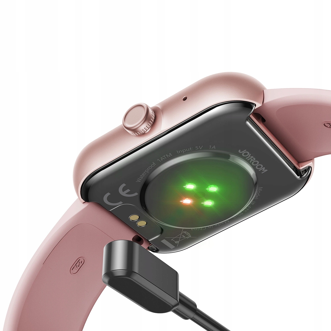 Różowy smartwatch jest ładowany, odsłaniając czujniki i nazwę marki, Joyroom, na odwrocie.