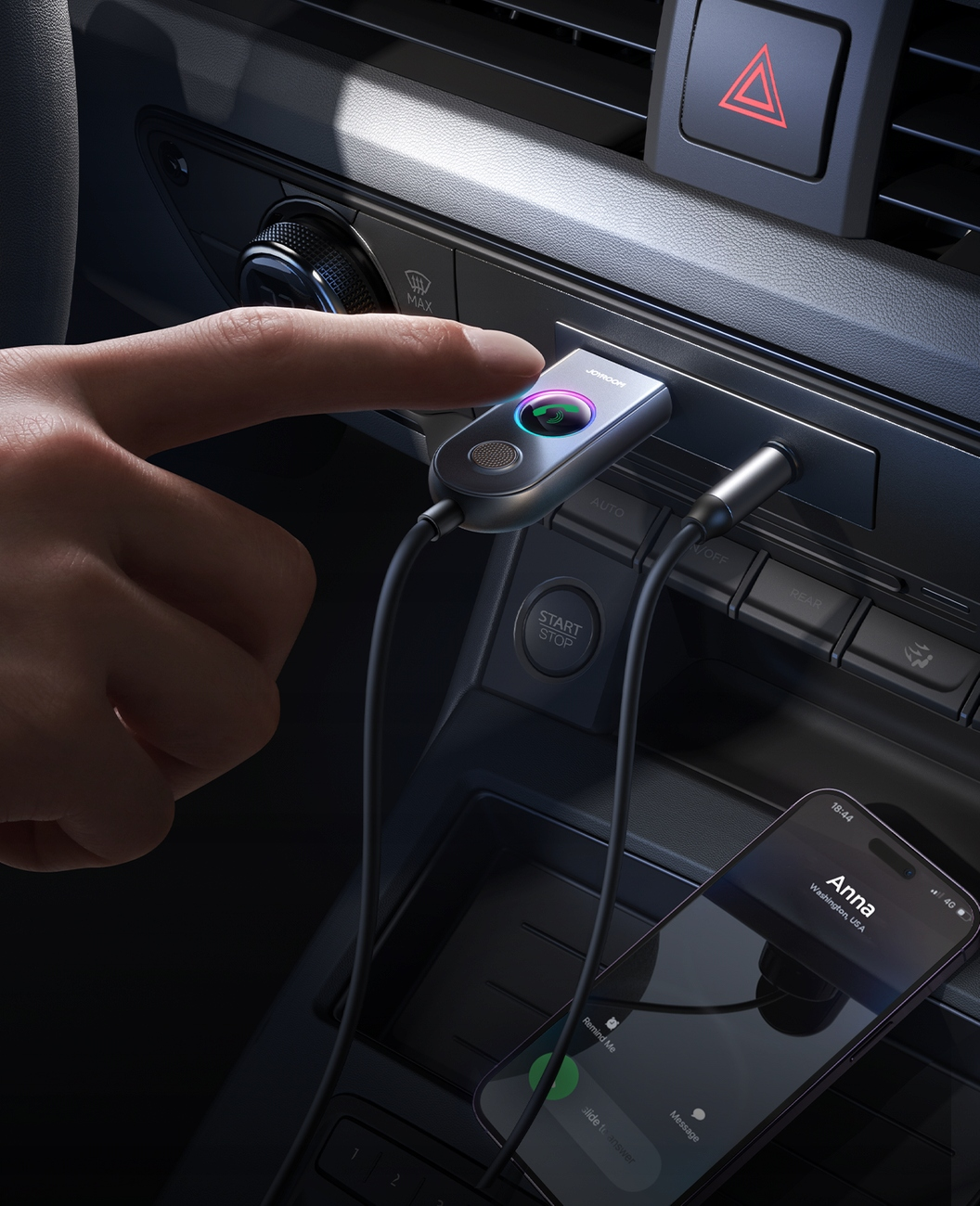 Eine Hand steckt einen Joyroom-Adapter in das Armaturenbrett eines Autos. Ein Telefon mit Anrufbildschirm ist sichtbar.