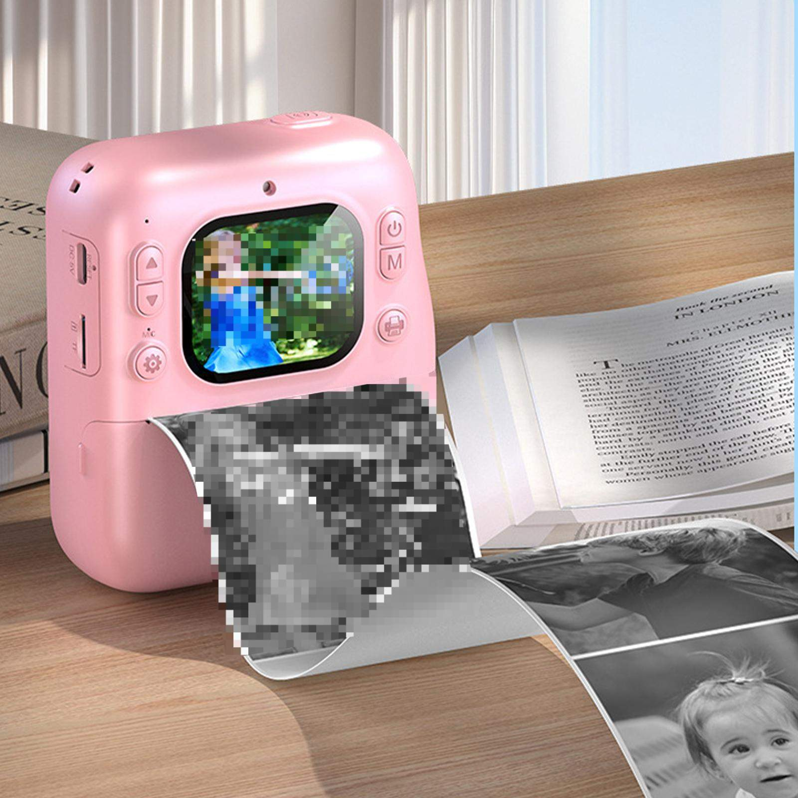 Eine rosa Sofortbildkamera druckt ein Foto. Ein Buch und gedruckte Fotos befinden sich im Hintergrund.