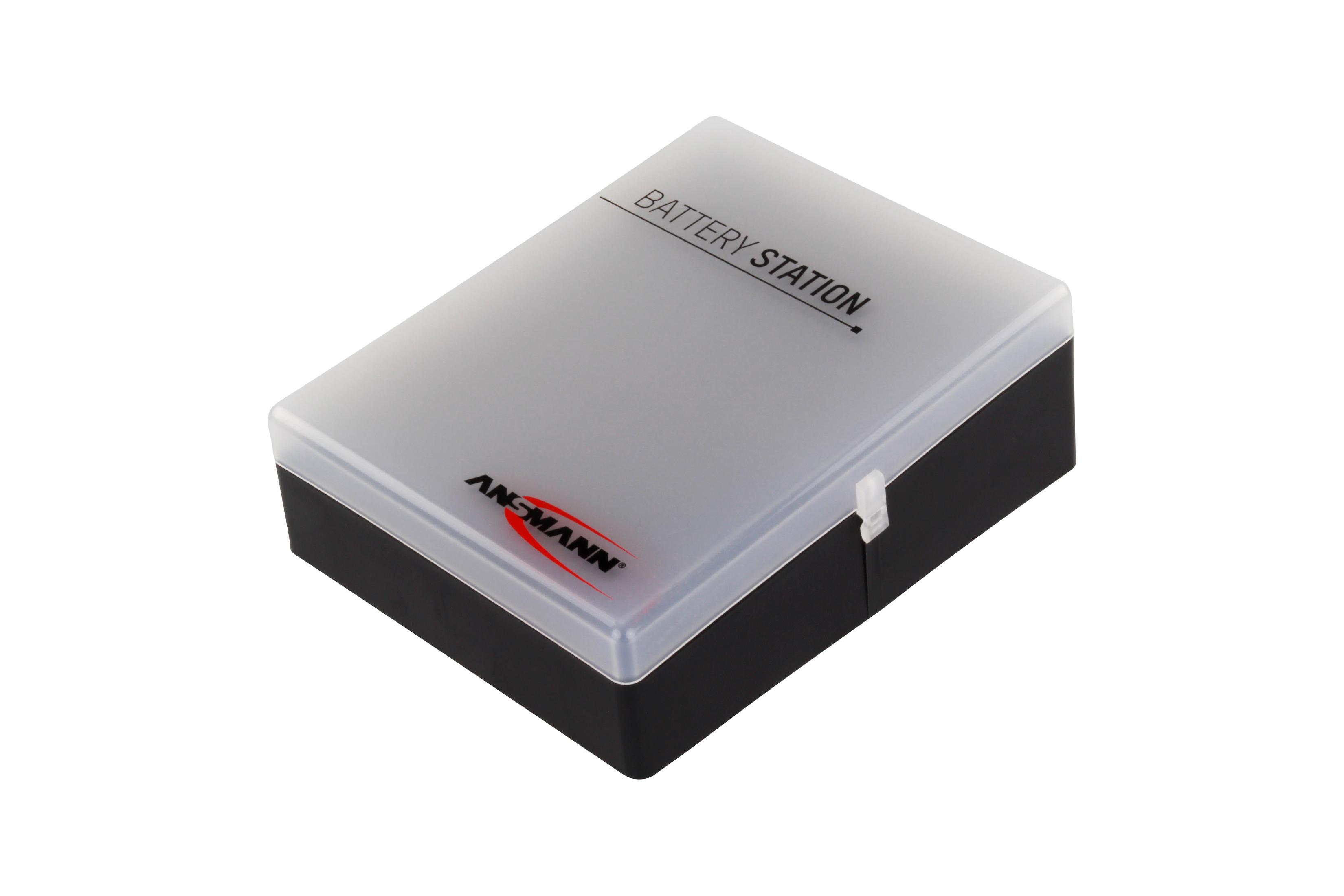Eine schwarze und graue Ansmann Batteriestation-Box mit einem durchsichtigen Kunststoffdeckel auf einem weißen Hintergrund.