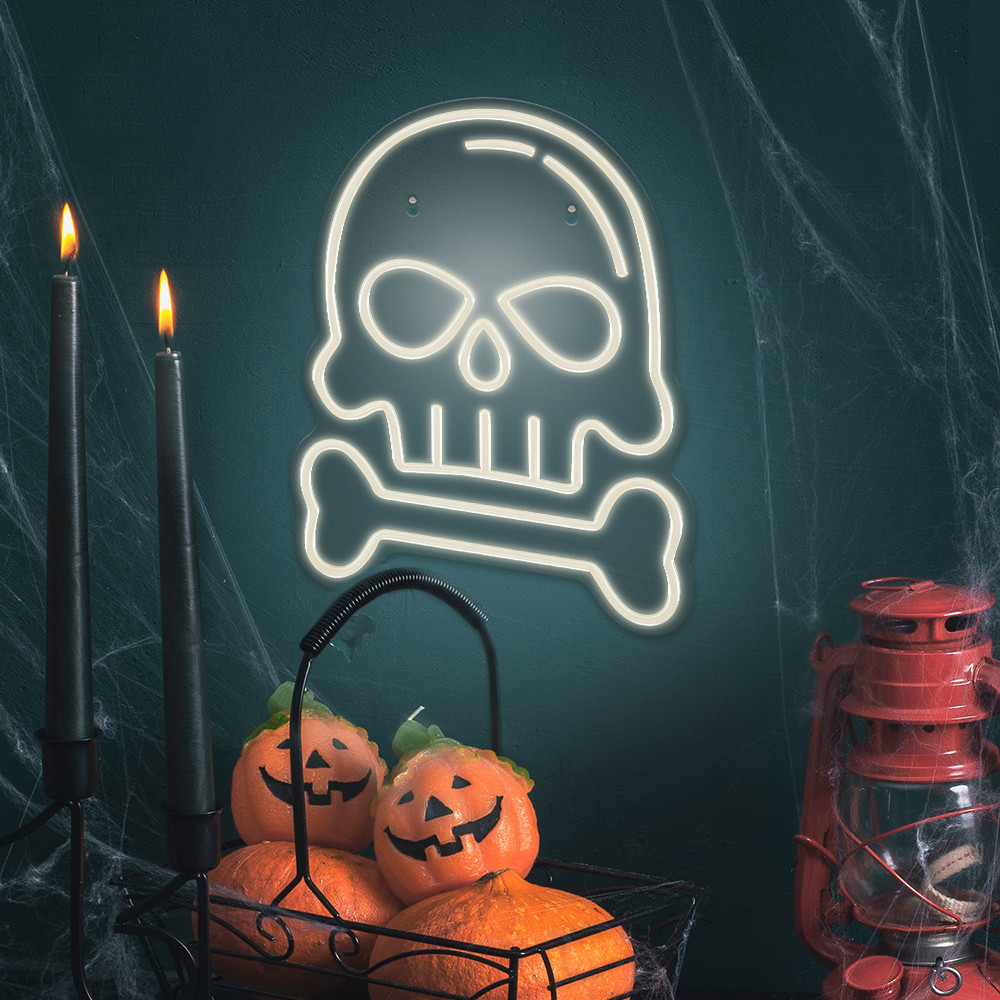 Halloween-Dekoration mit einem Totenkopf-Neon-Schild, Kerzen, Kürbissen und einer Laterne auf dunklem Teal-Hintergrund.
