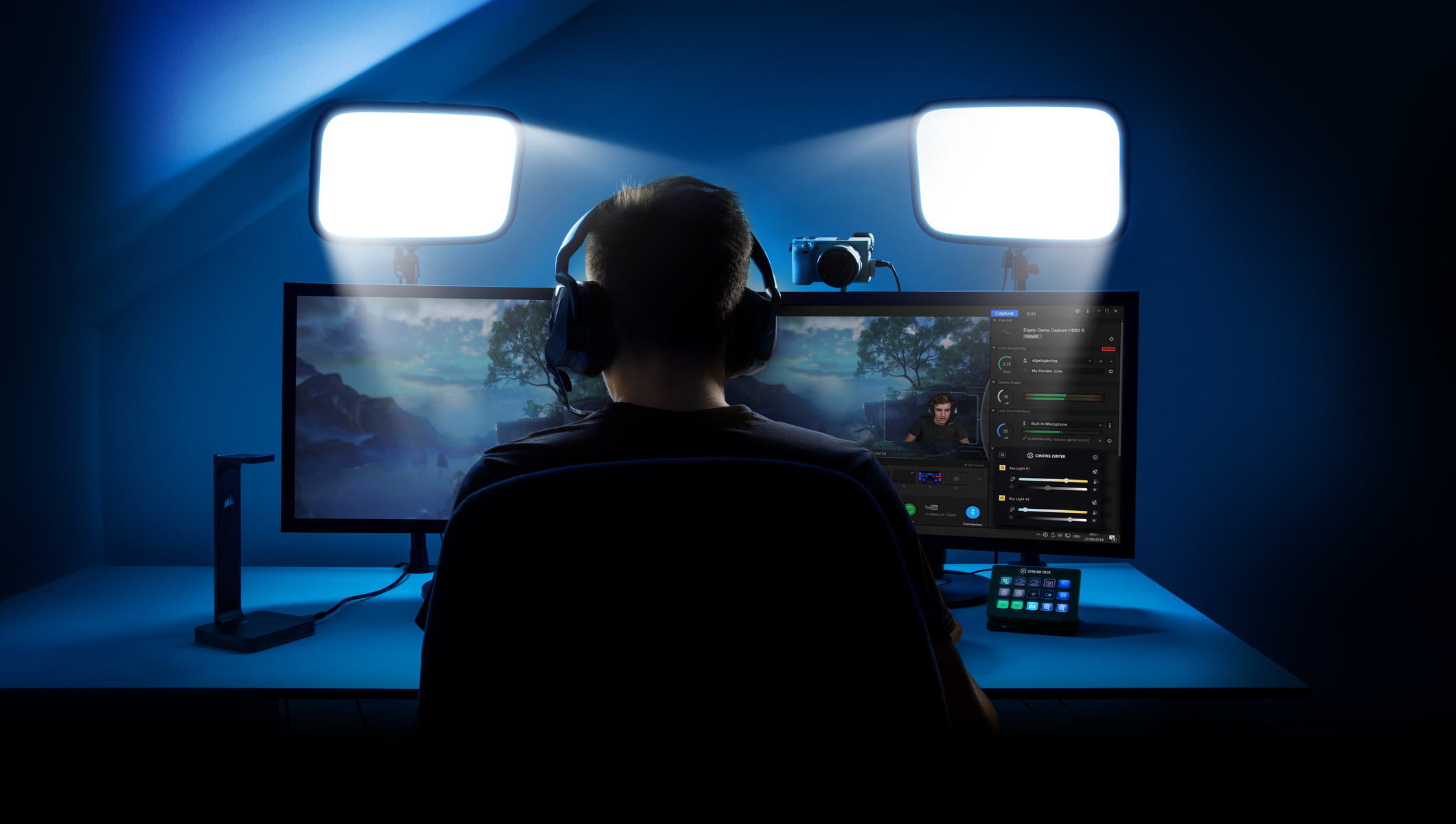 Una persona è seduta a una scrivania con due monitor e due luci principali, creando una configurazione di streaming illuminata di blu.
