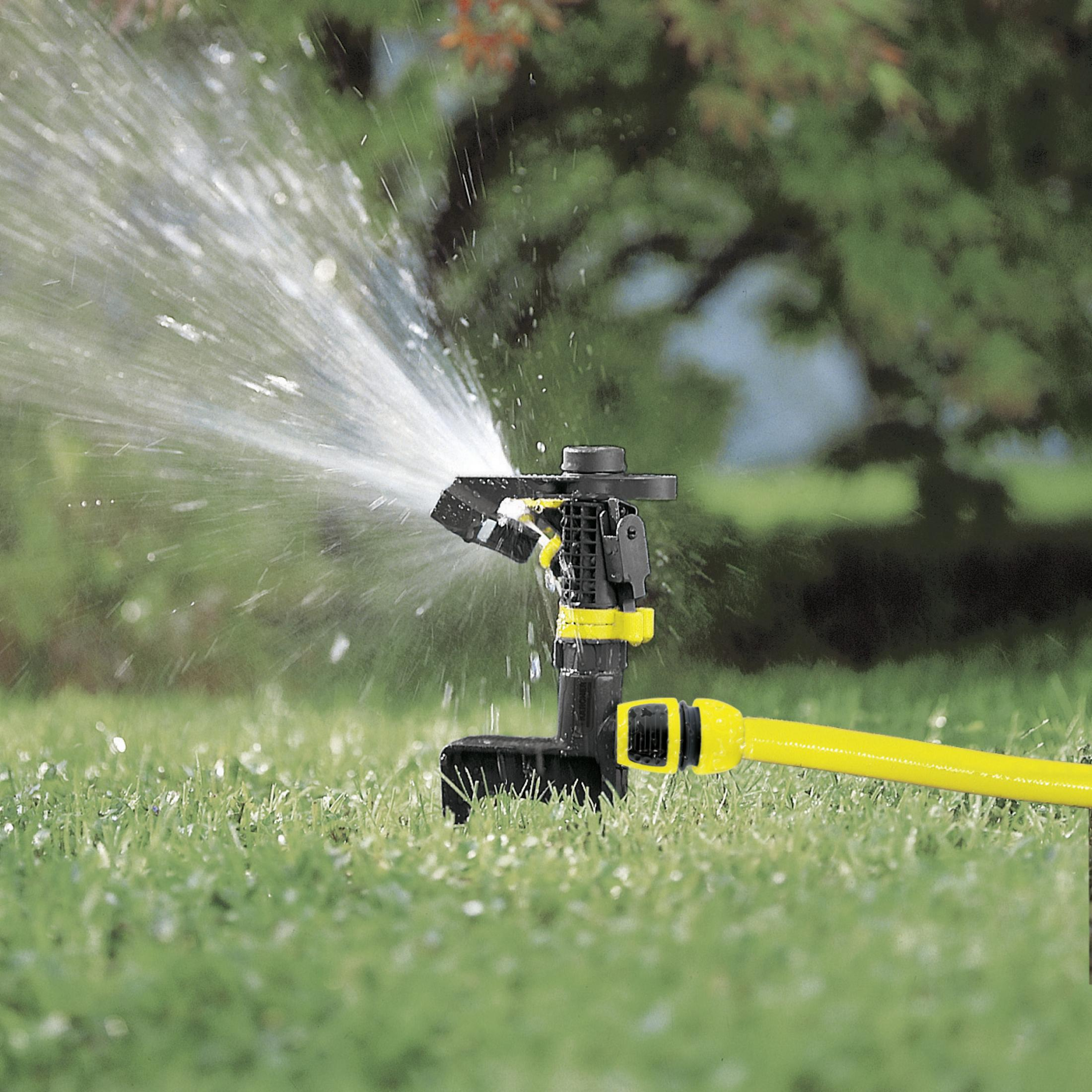 Rasensprenger, der Wasser auf Gras in einer Gartenanlage sprüht.