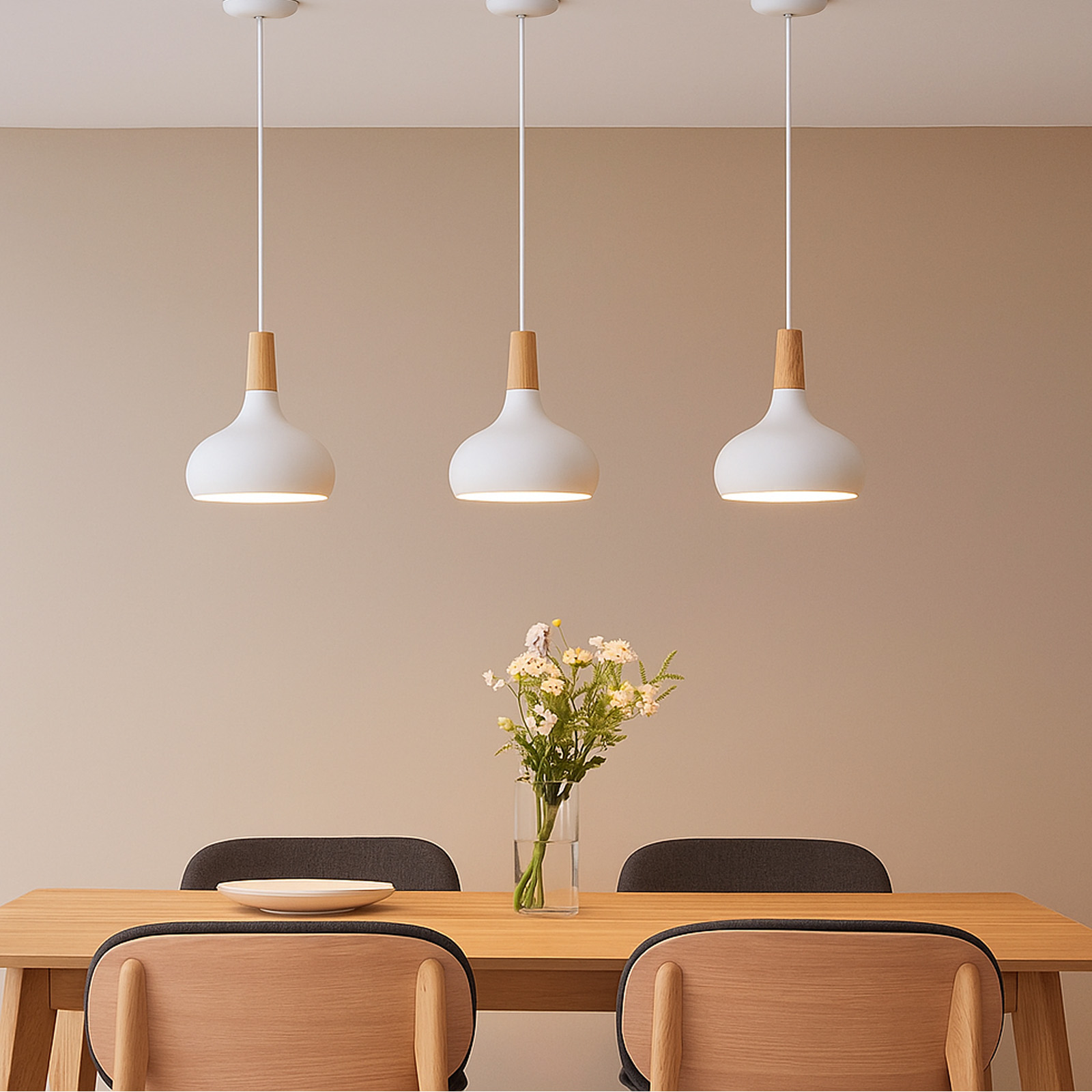 Tres lámparas colgantes blancas con detalles de madera cuelgan sobre una mesa de madera con flores, platos y sillas.