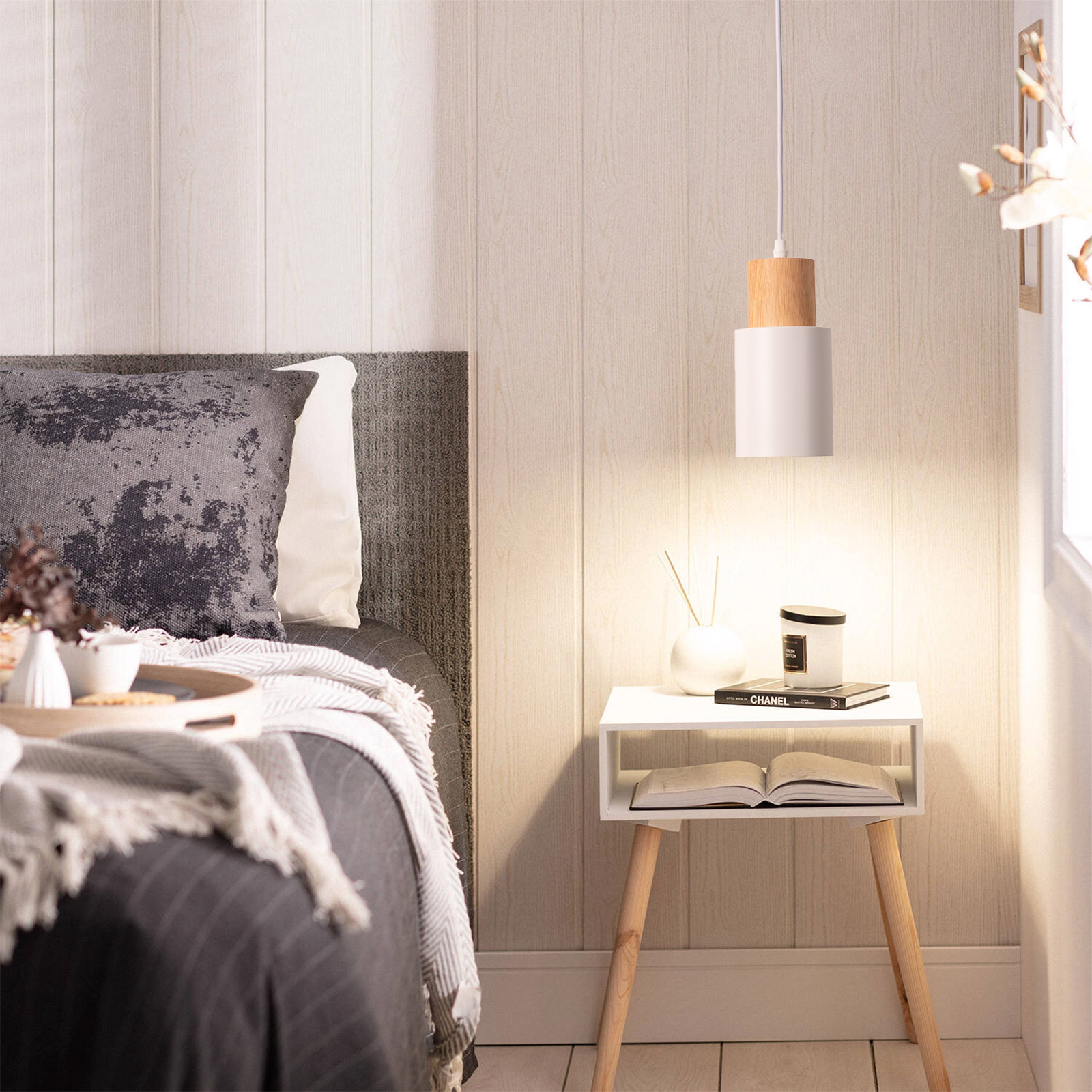 Una lámpara colgante blanca y de madera cuelga sobre una mesita de noche en un moderno dormitorio.