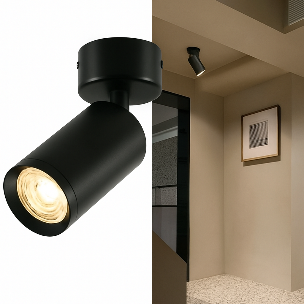 Un foco negro, montado en un techo. El foco está encendido y la habitación tiene una iluminación cálida.