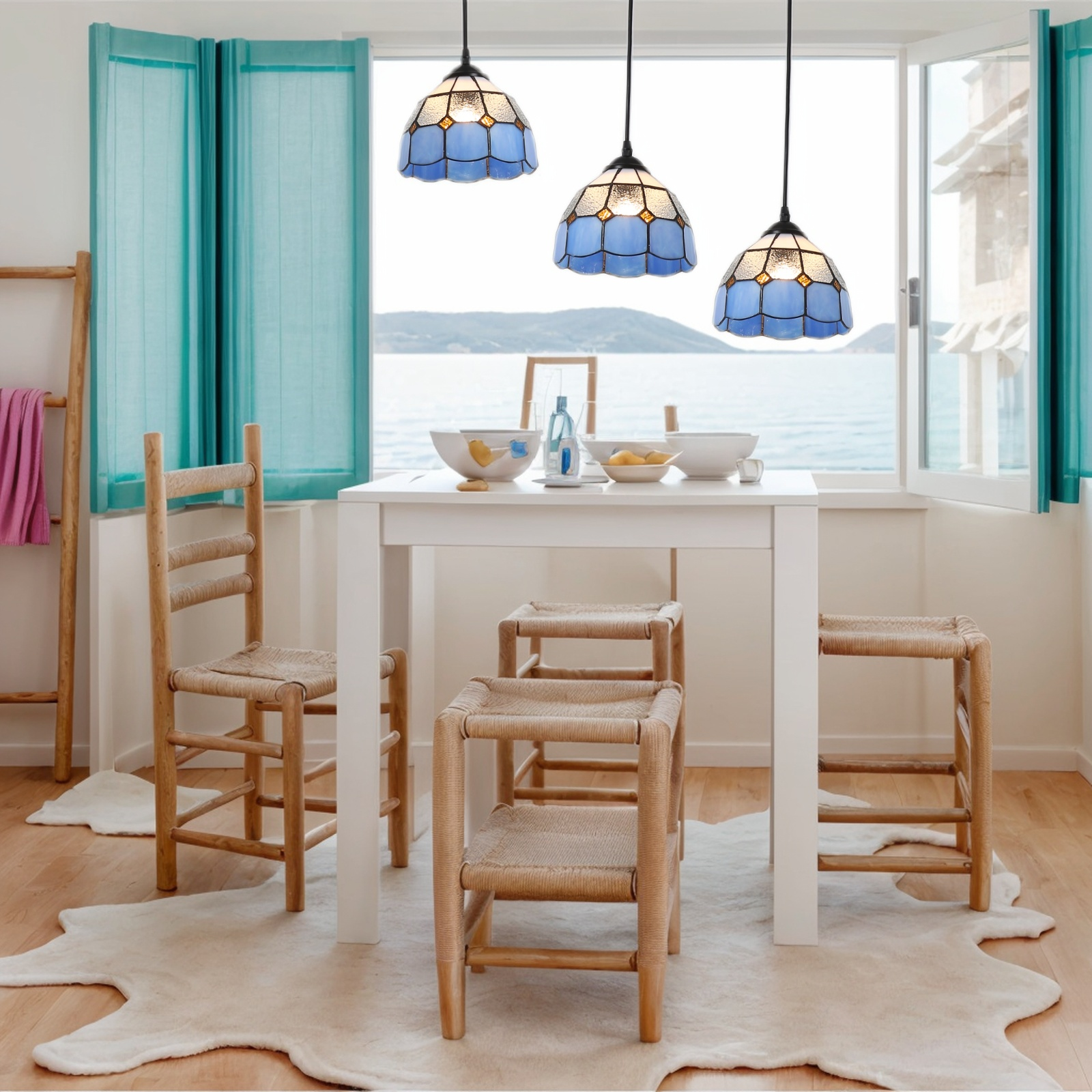 Un comedor luminoso con tres lámparas colgantes azules y blancas sobre una mesa blanca.
