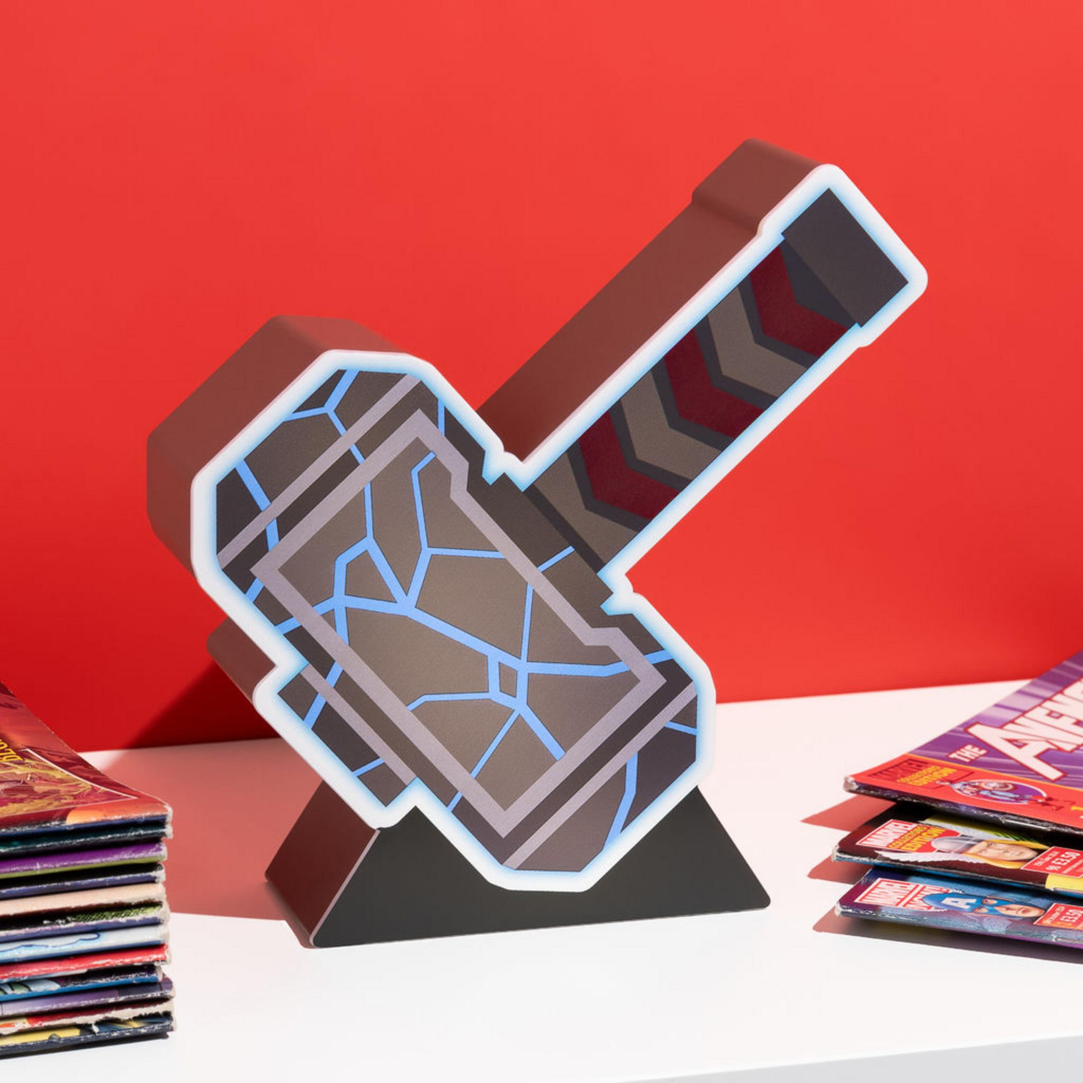Ein Hammerobjekt mit blauen Rissen, auf einer weißen Oberfläche mit Comics im Hintergrund.