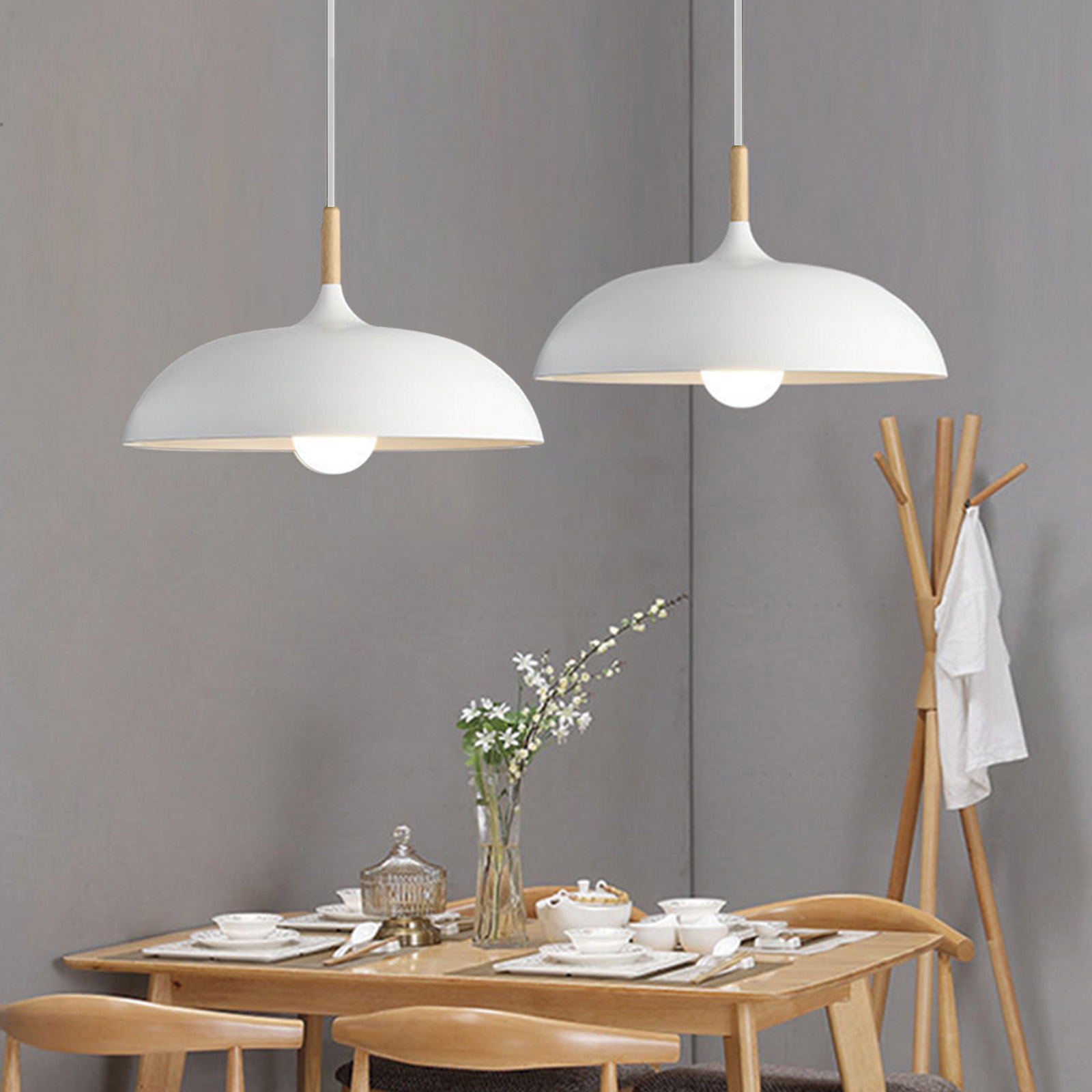 Comedor con una mesa de madera y dos lámparas colgantes blancas colgando encima.