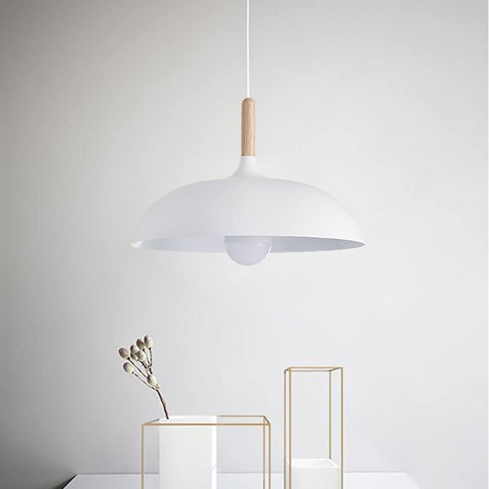 Una lámpara colgante blanca cuelga sobre una mesa con elementos decorativos contra una pared blanca.