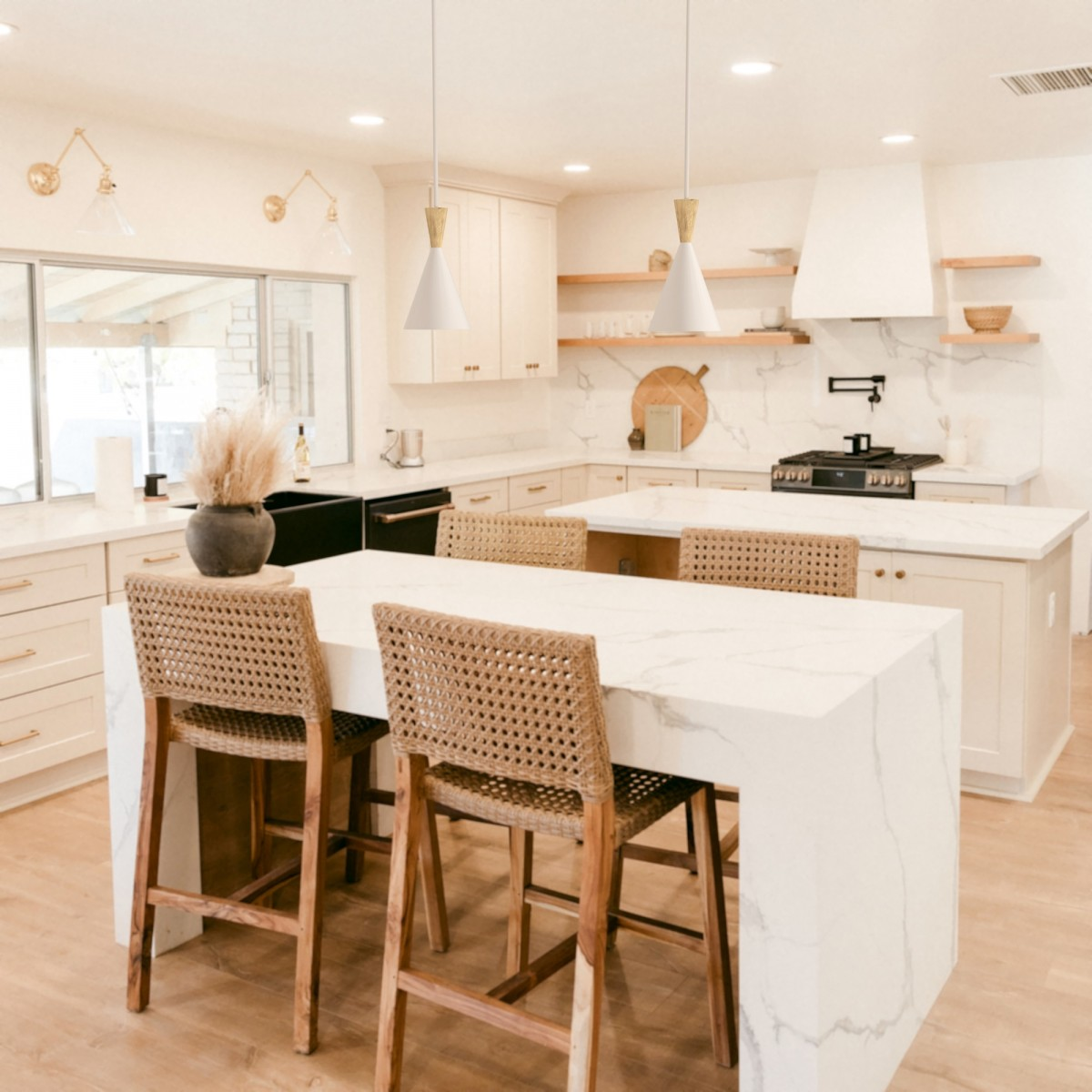 Una cocina con encimeras blancas, sillas de madera y dos lámparas colgantes.