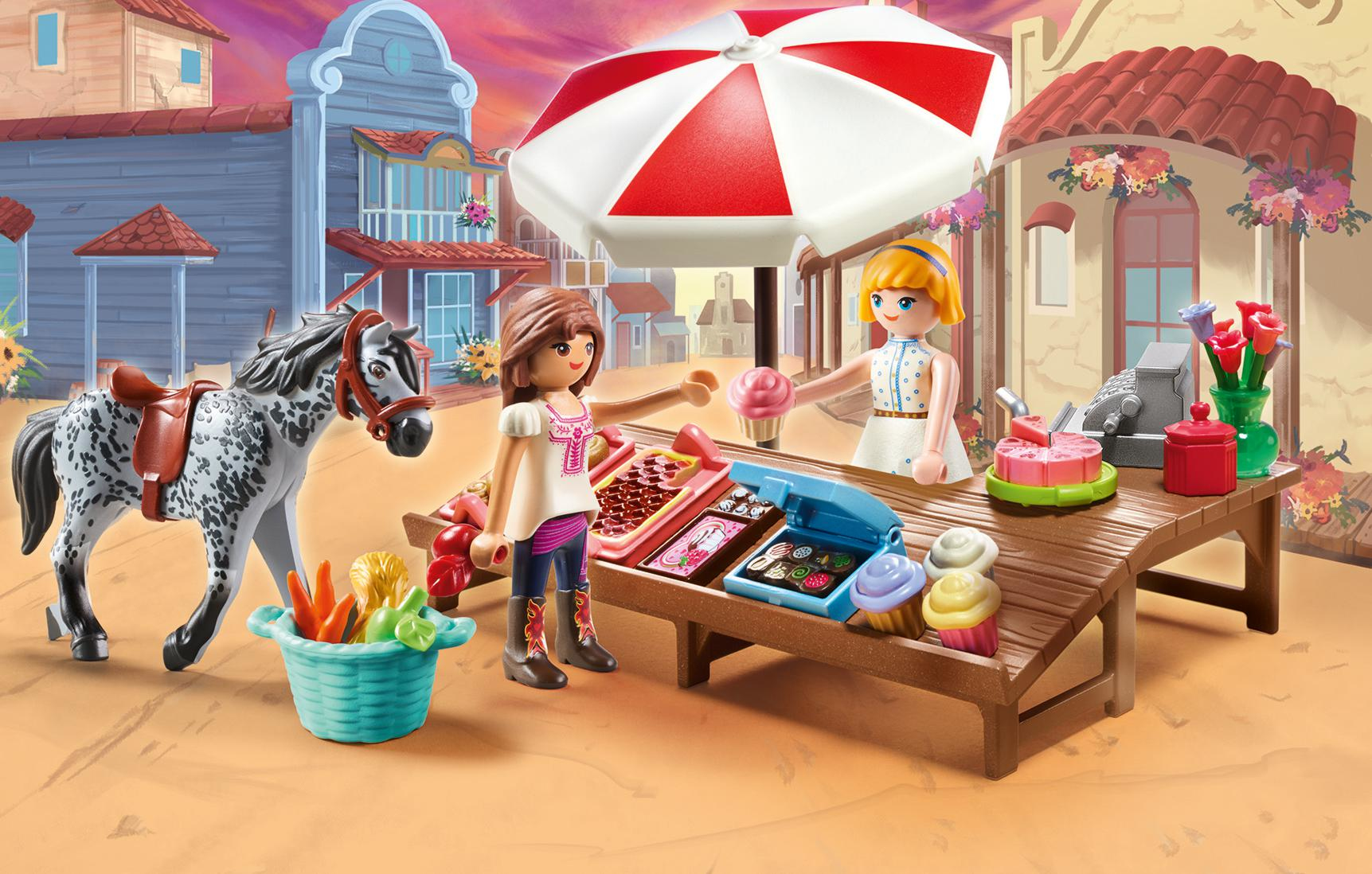 Una escena de Playmobil con un caballo, gente y un puesto de mercado con dulces y cupcakes.