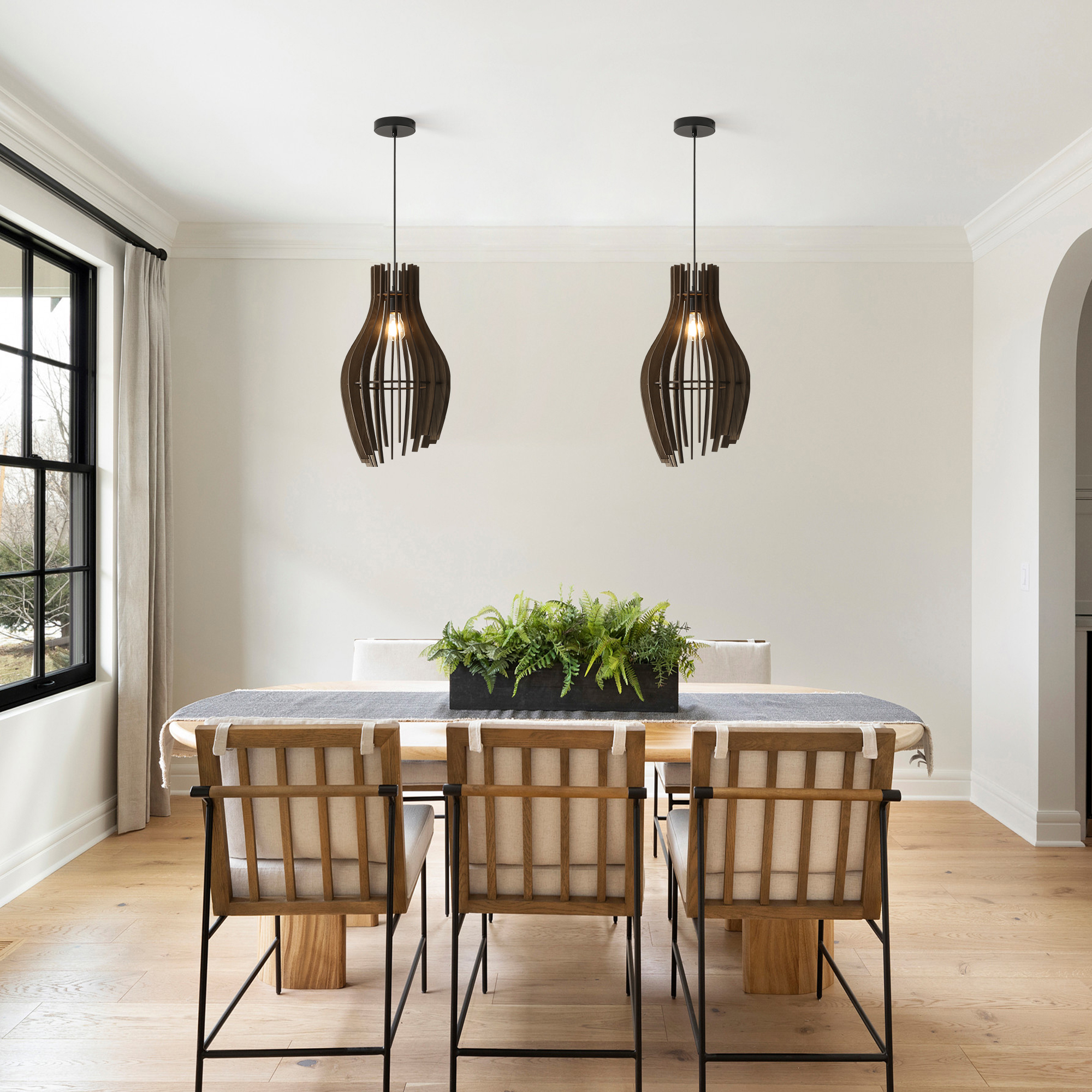 Dos lámparas colgantes de madera negra cuelgan sobre una mesa de comedor con sillas y un centro de mesa.