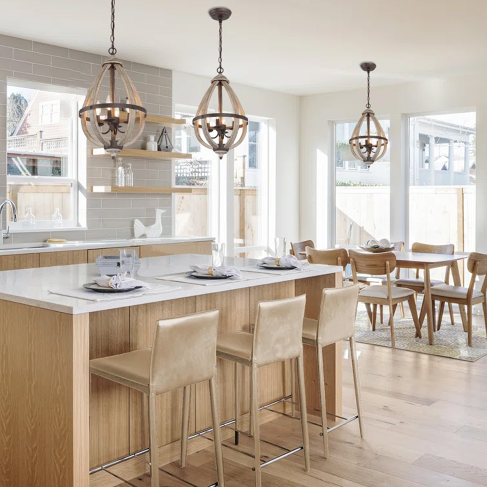 Cocina con tres candelabros de madera colgando sobre una isla con taburetes de bar.