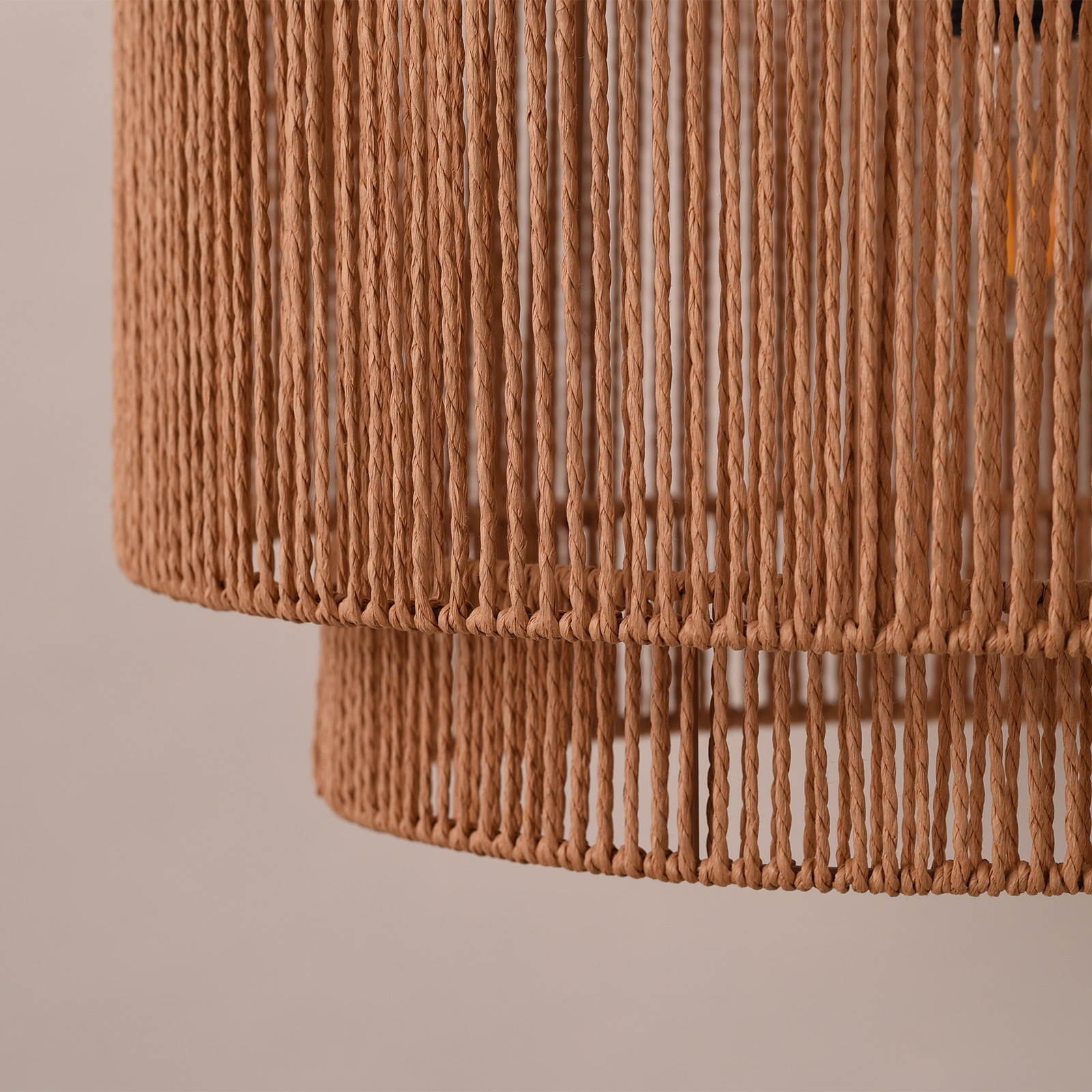 Un primer plano de una lámpara colgante beige tejida de dos niveles, que muestra la textura y los detalles del diseño.