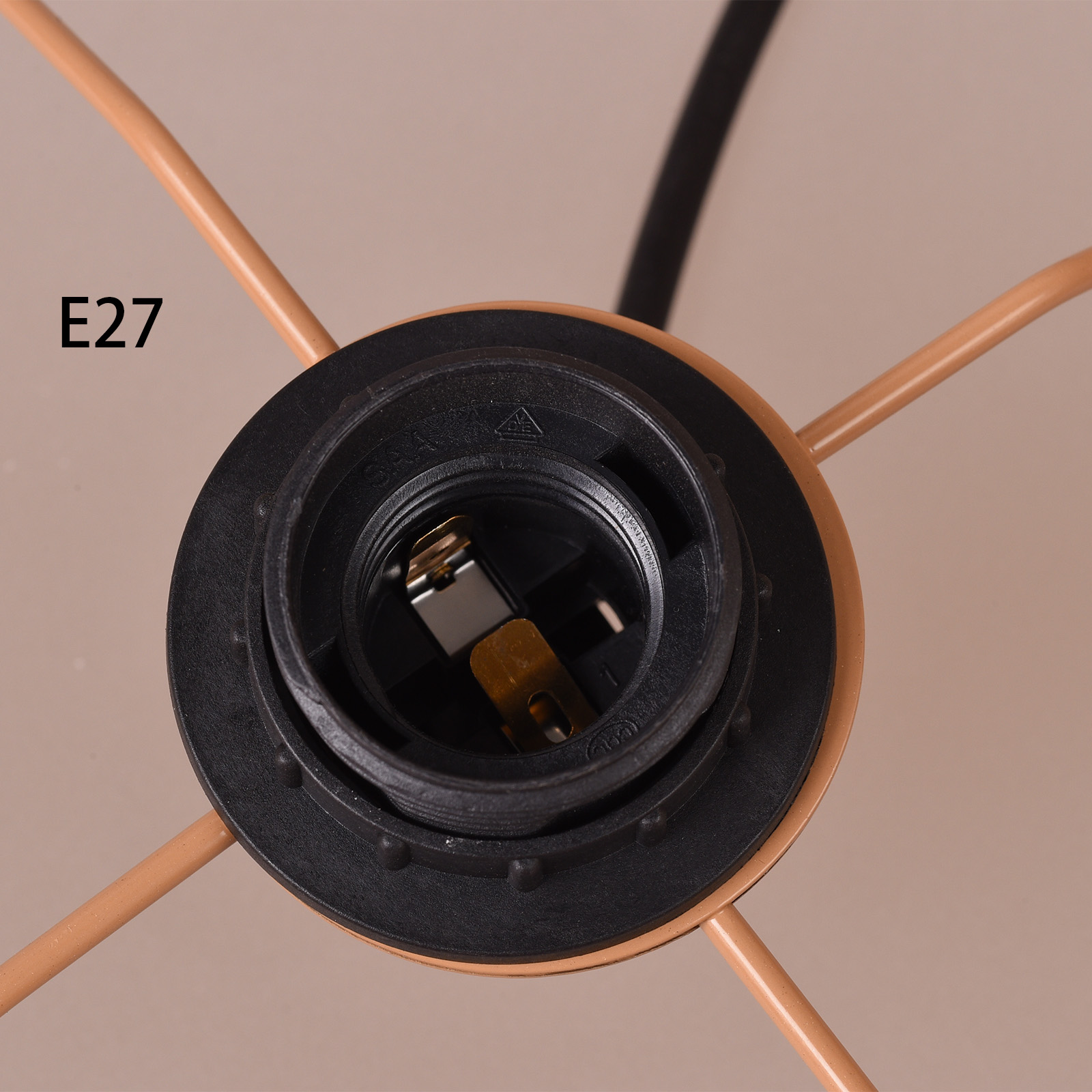 Primer plano de un portalámparas negro con etiqueta E27 y cables beige.