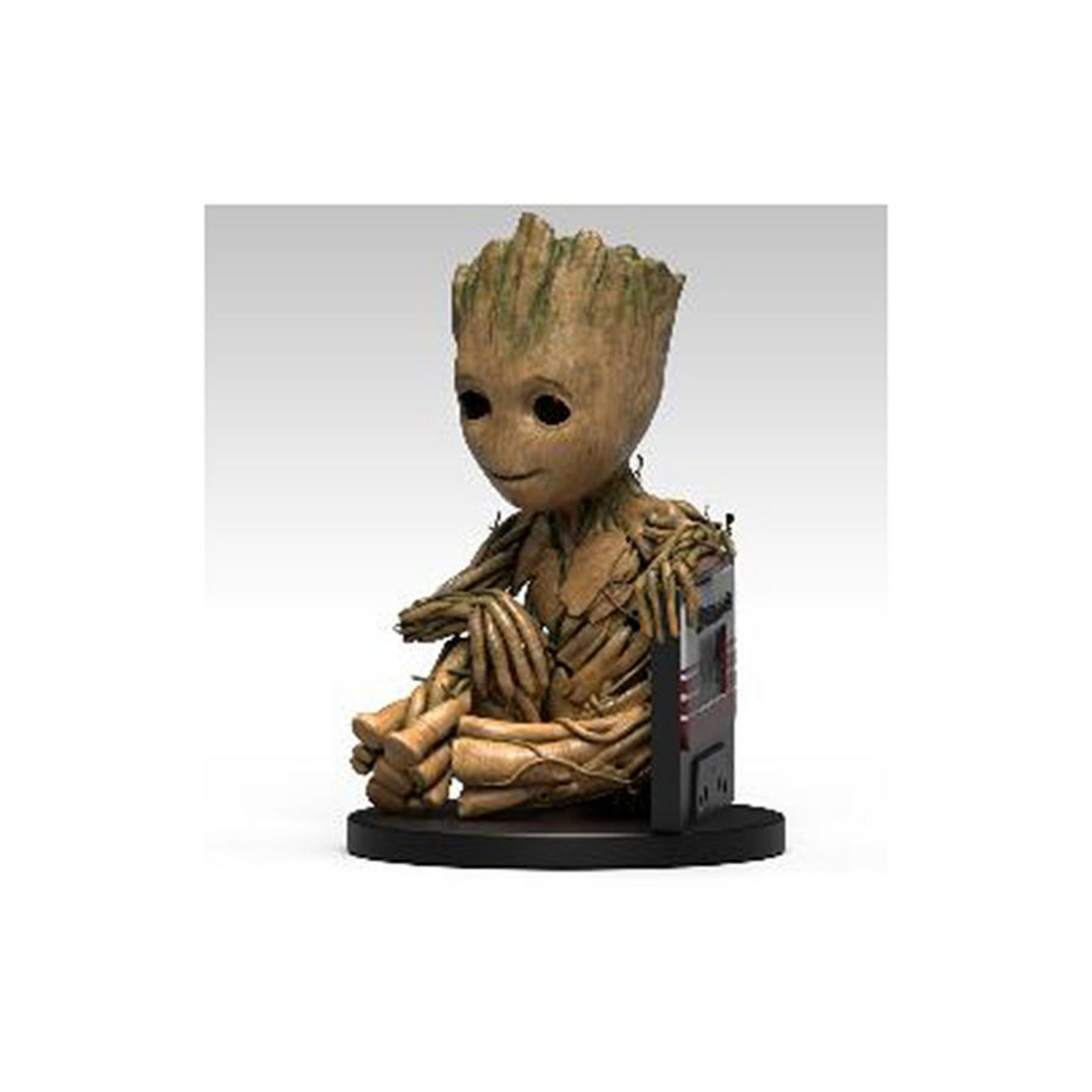 Una figura de Groot sentado. Textura de madera marrón, ojos pequeños y una ligera sonrisa. Se sienta sobre una base negra.