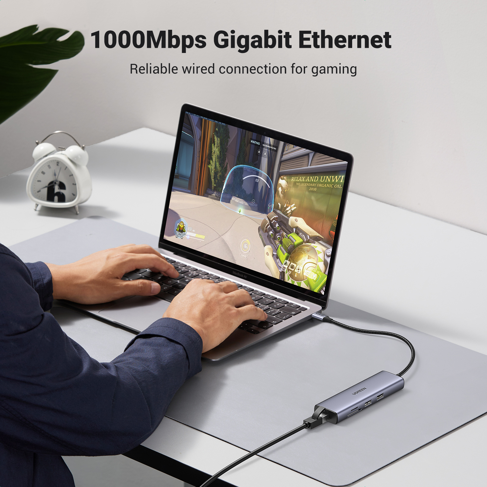 Una persona sta giocando a un gioco su un laptop collegato a un hub USB-C UGREEN su una scrivania.