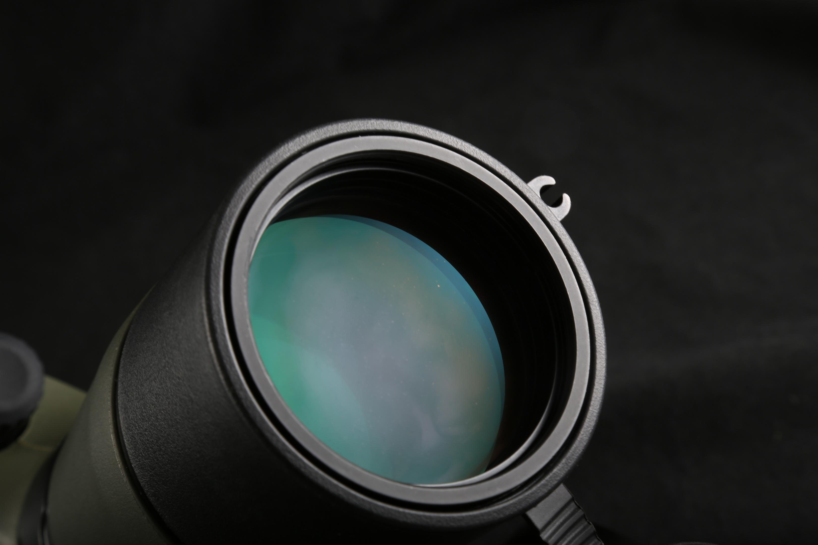 Un primer plano de la lente de un telescopio muestra una superficie verde reflectante contra el negro.
